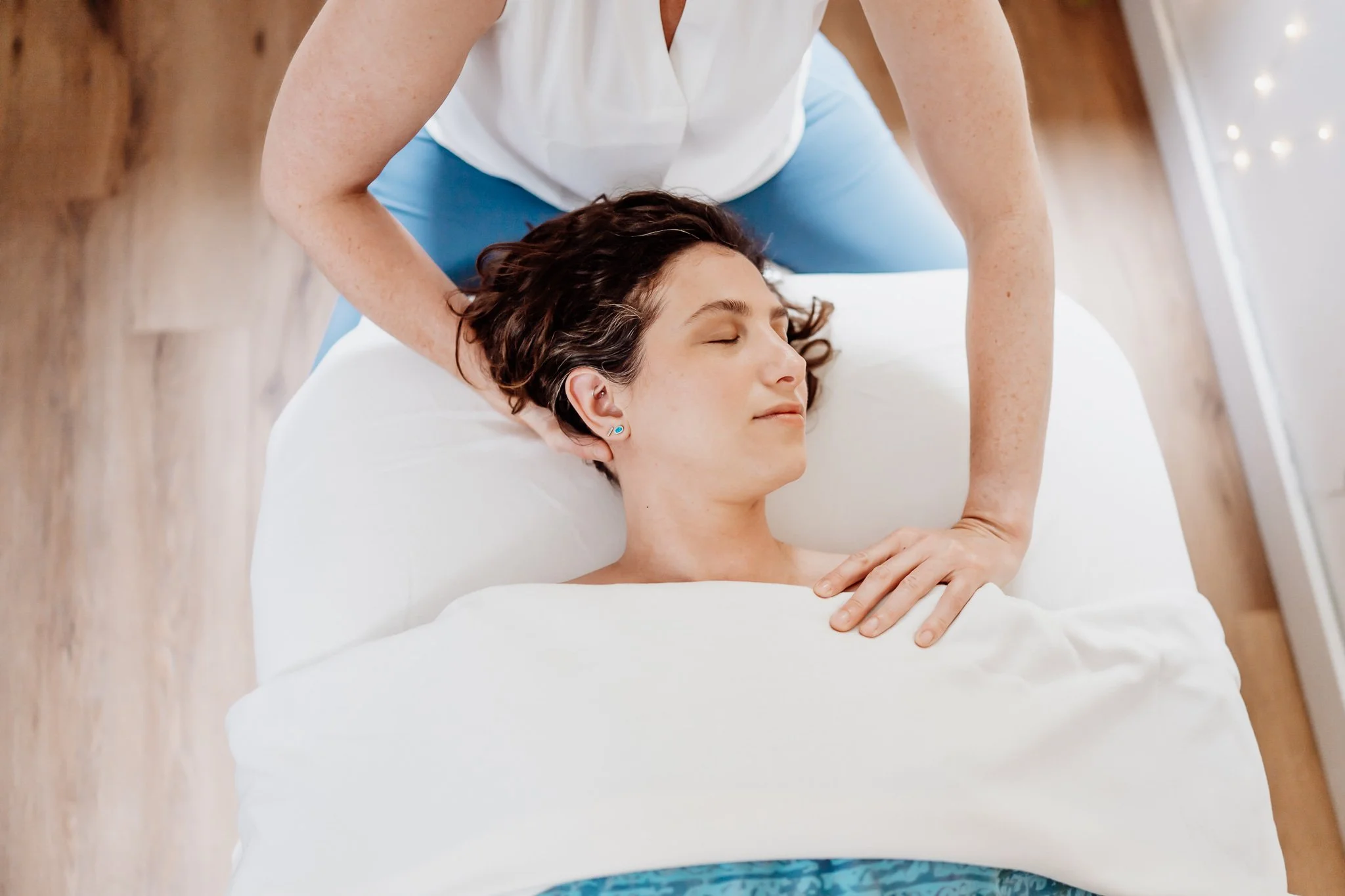 Female massage client receiving calming therapeutic neck massage for stress relief in Amber Howard's Bar Harbor, Maine massage studio