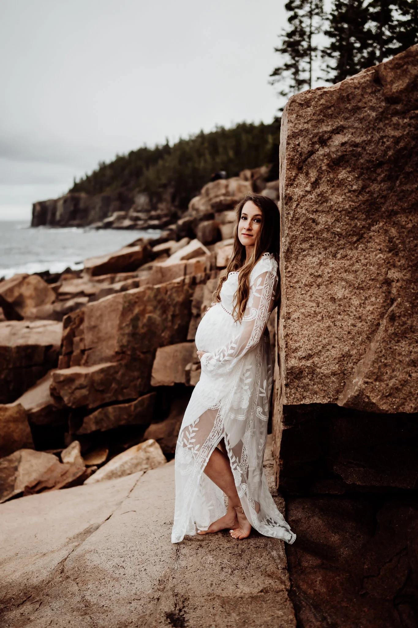 Amber Howard poses for a maternity photo by the ocean in Acadia National Park on Mount Desert Island, Maine