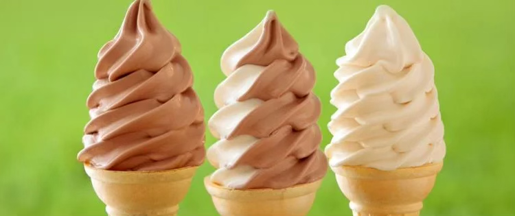 Three vegan soft serve ice cream cones with chocolate, chocolate vanilla swirl, and vanilla flavors against a green background.