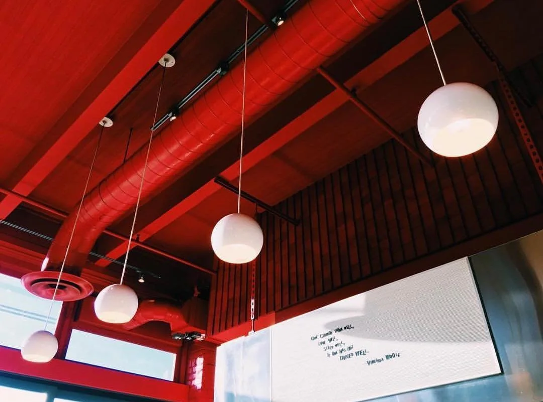 Interior view of a wooden ceiling with exposed beams, electrical wiring, and hanging light fixtures.