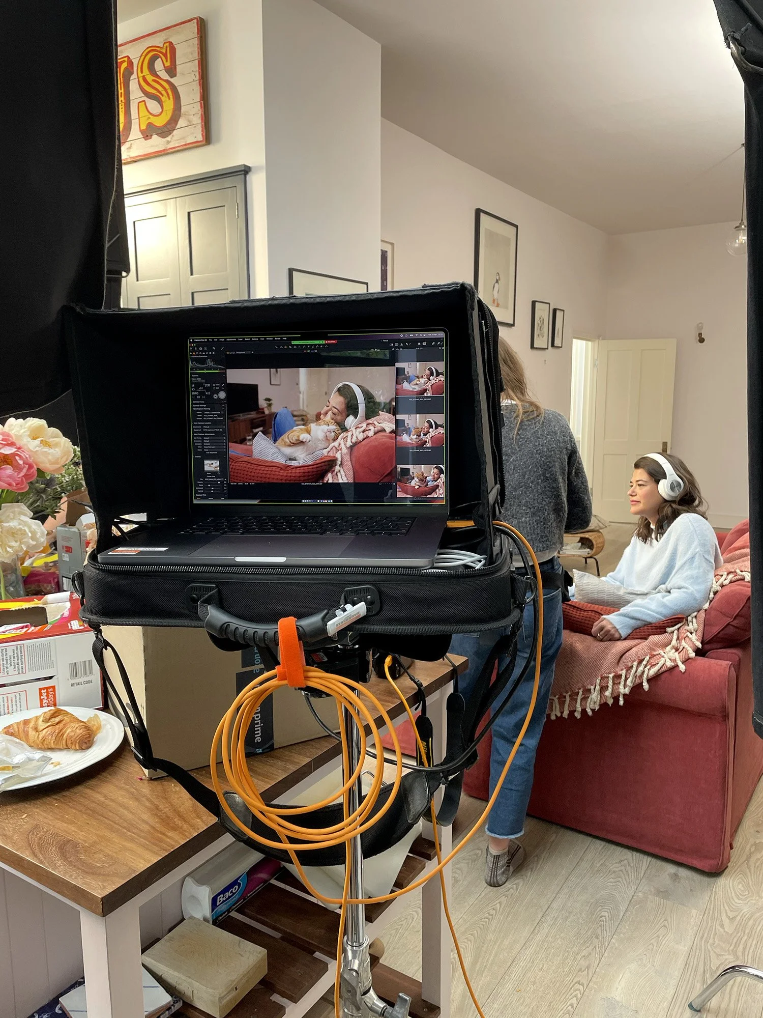 A director adjusting the set on an advertising photoshoot featuring a woman wearing headphones and a cat