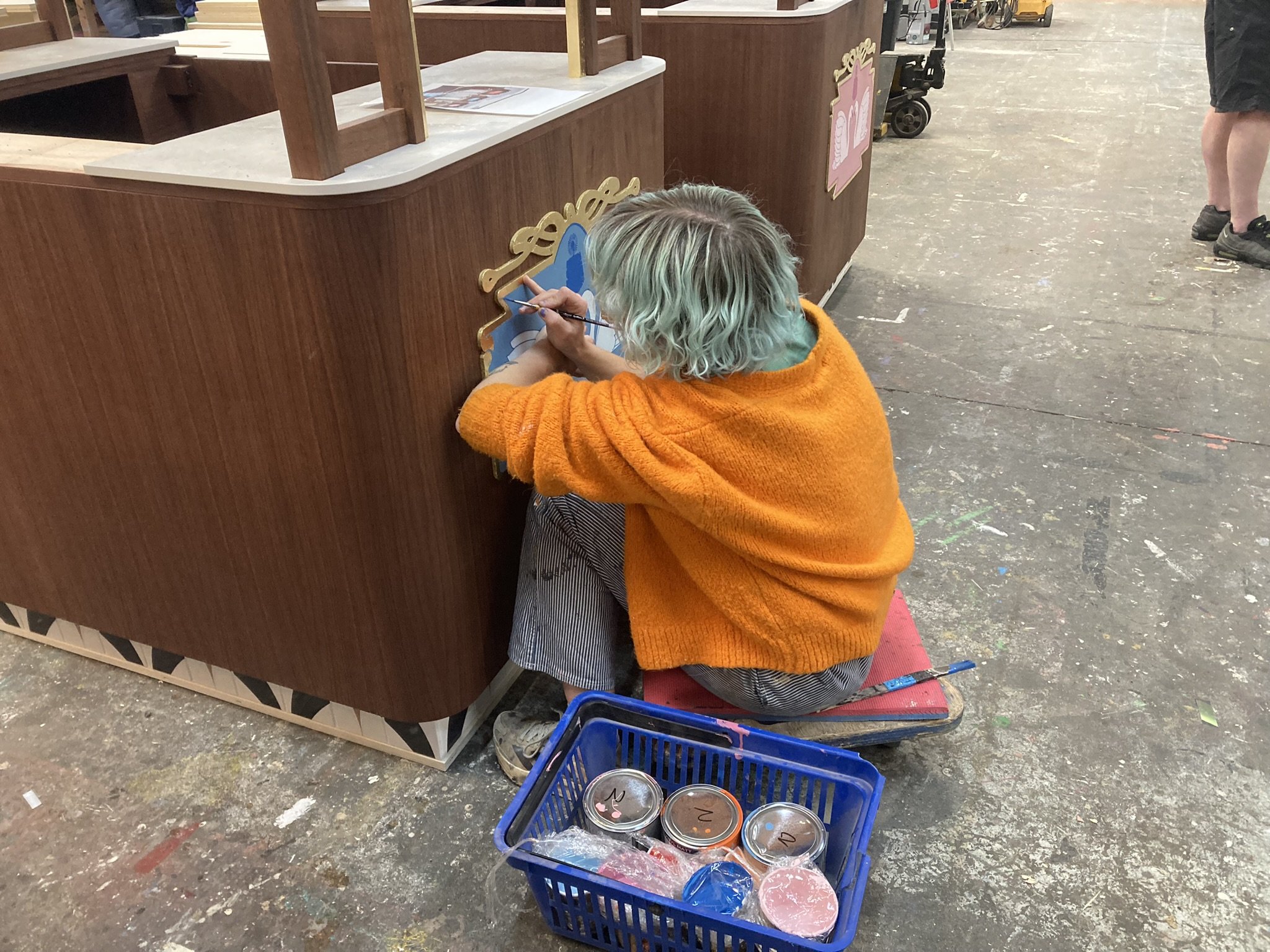 Scenic artist hand painting a large-scale prop in Creator International's workshop