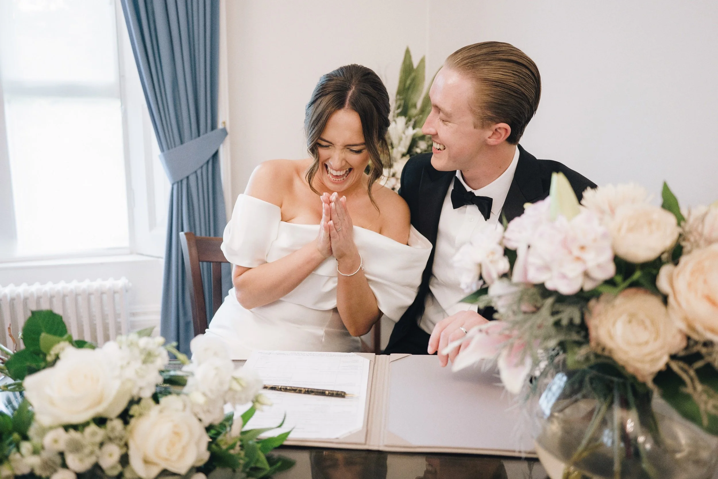 Bride celebrates as she finishes signing the legal wedding papers at her wedding in Guildford, Surrey