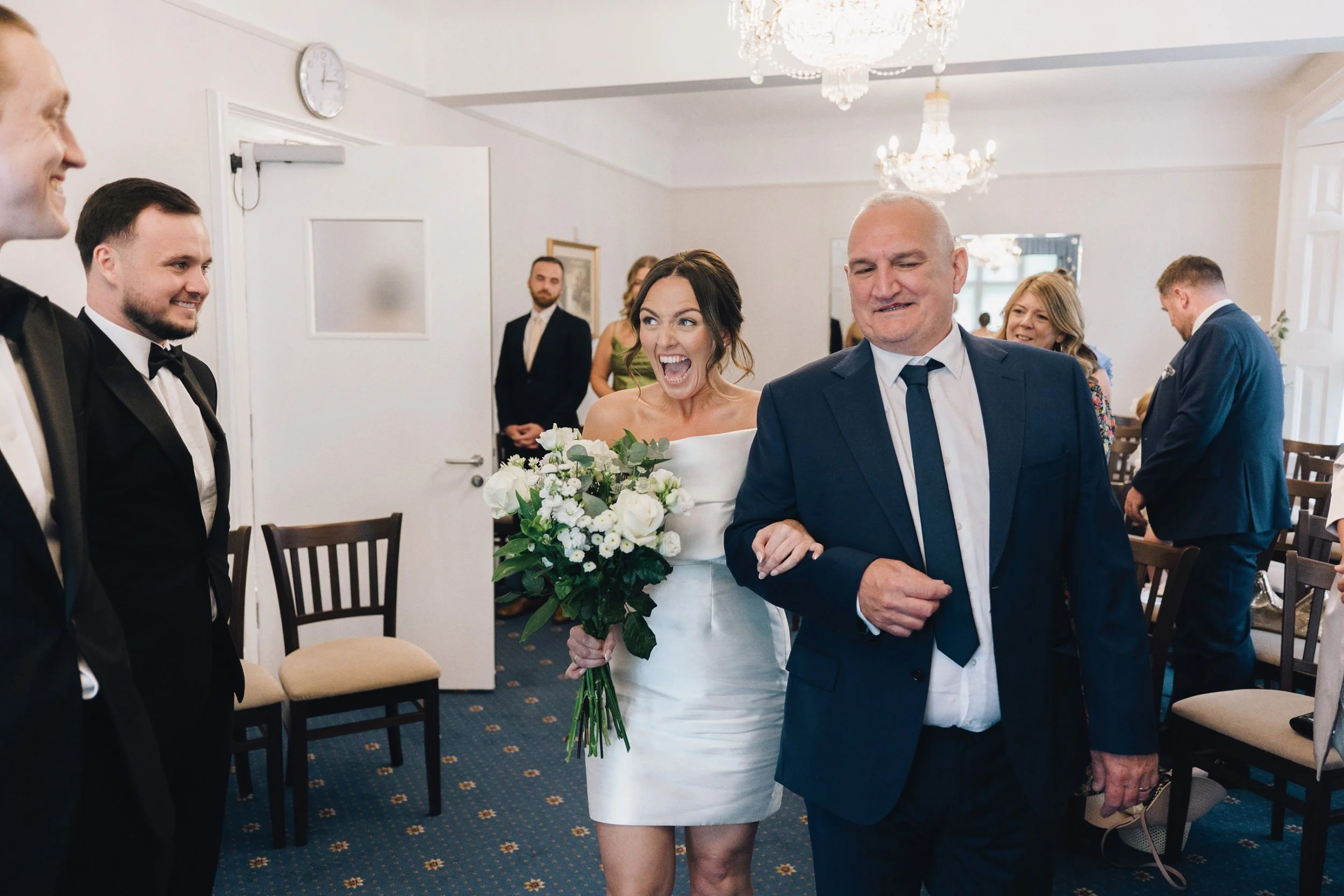 Photographer captures the moment the bride grins as she sees the groom for the first time at their Guildford wedding venue