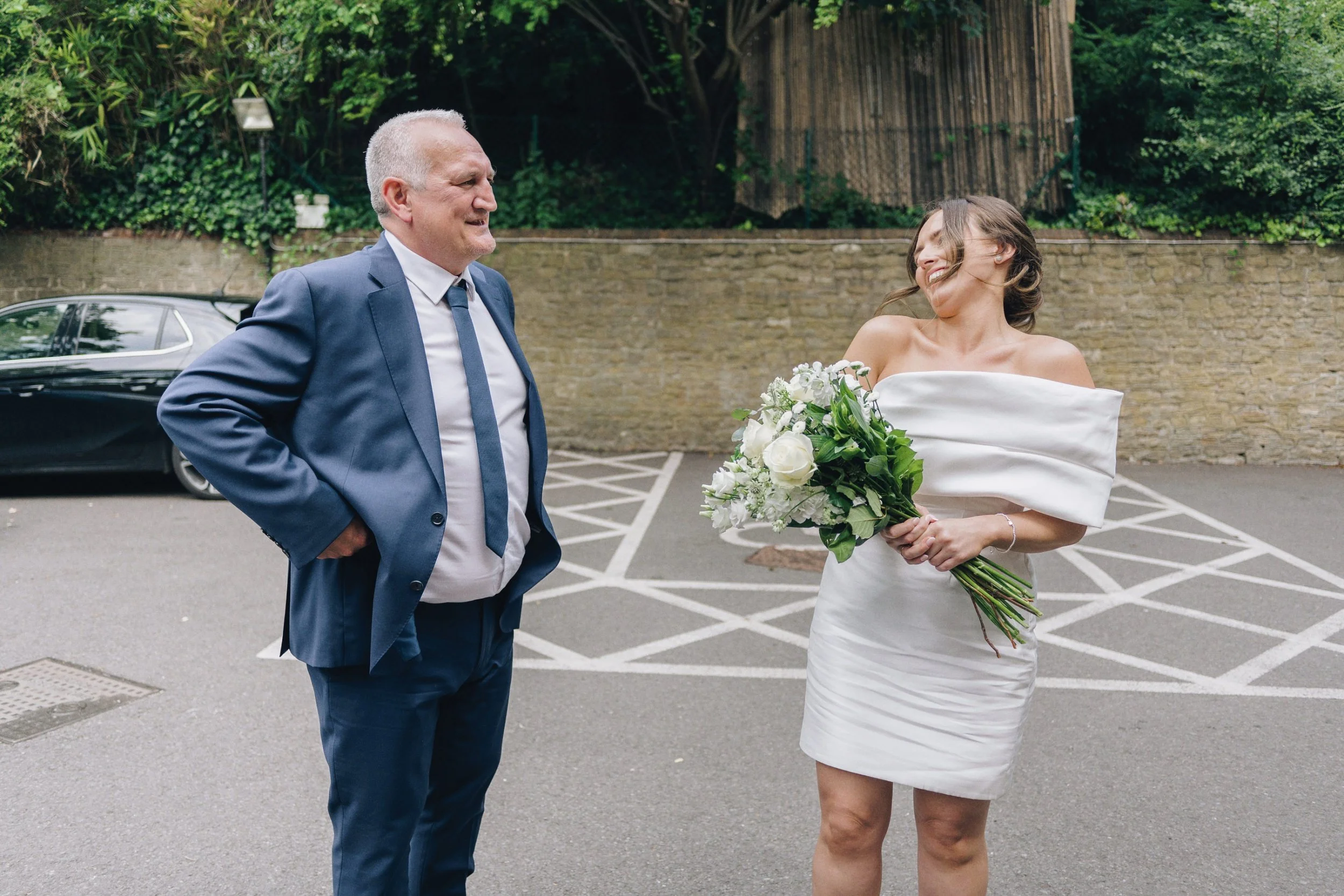 Bride and her father laughing together outside the Guildford wedding venue