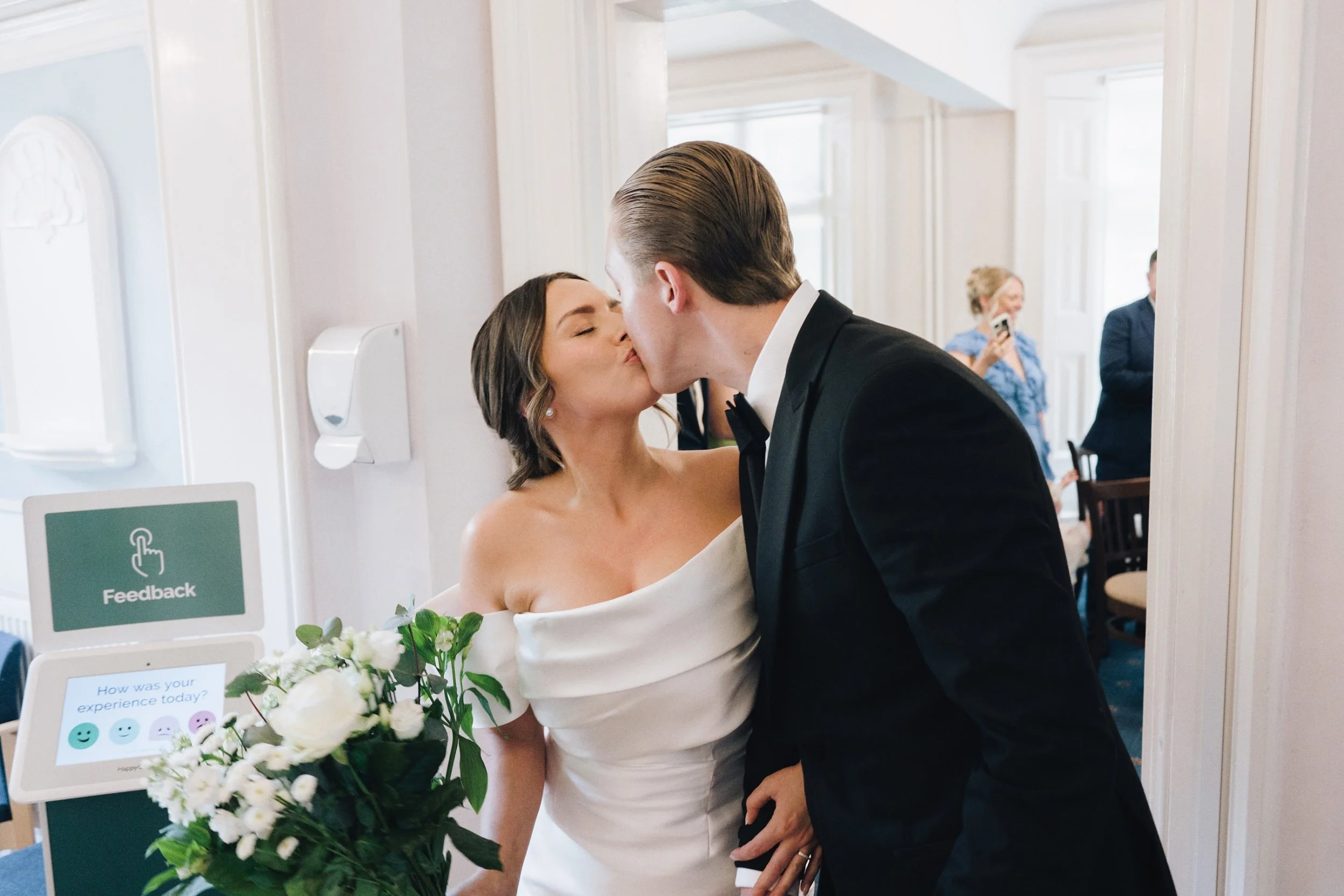 Bride and groom kiss as the photographer captures them leaving their wedding ceremony