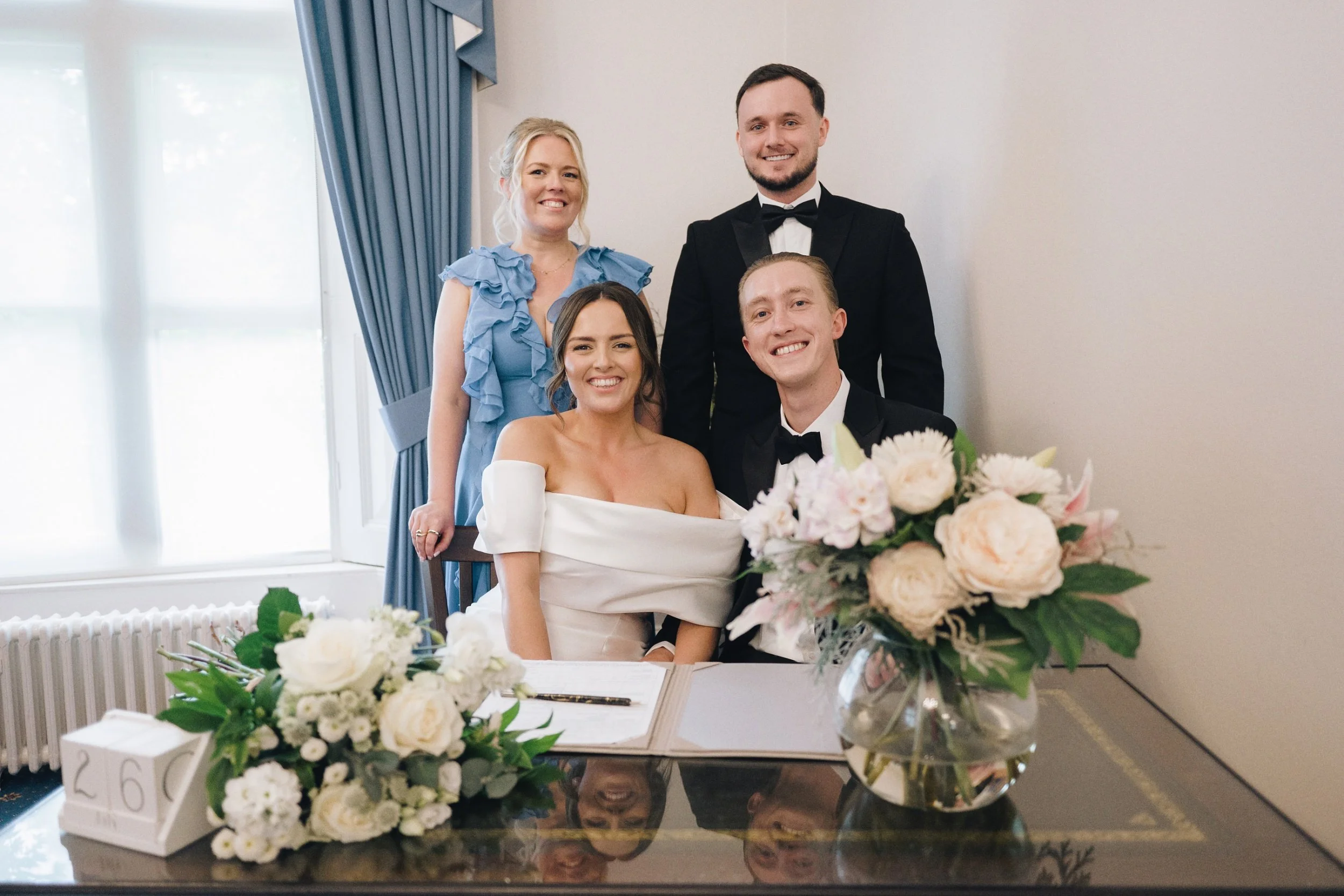 The newlyweds and their two witnesses smile for the wedding photographer at their Guildford wedding ceremony