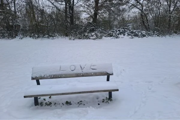 Verschneite Bank mit "Love" am Alsterlauf in Hamburg