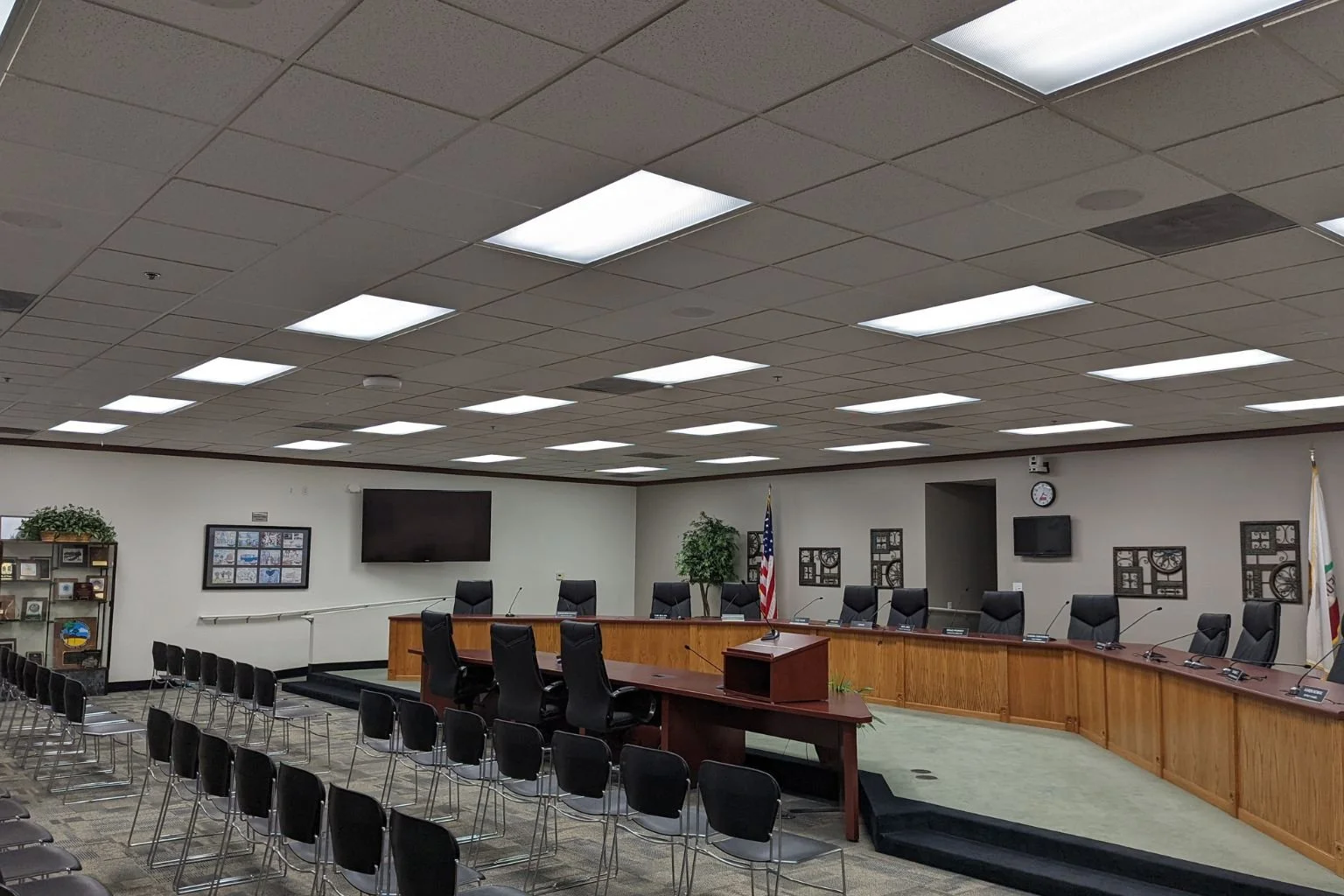 Electrician in Victorville installing commercial ceiling lighting in office or council chamber building.