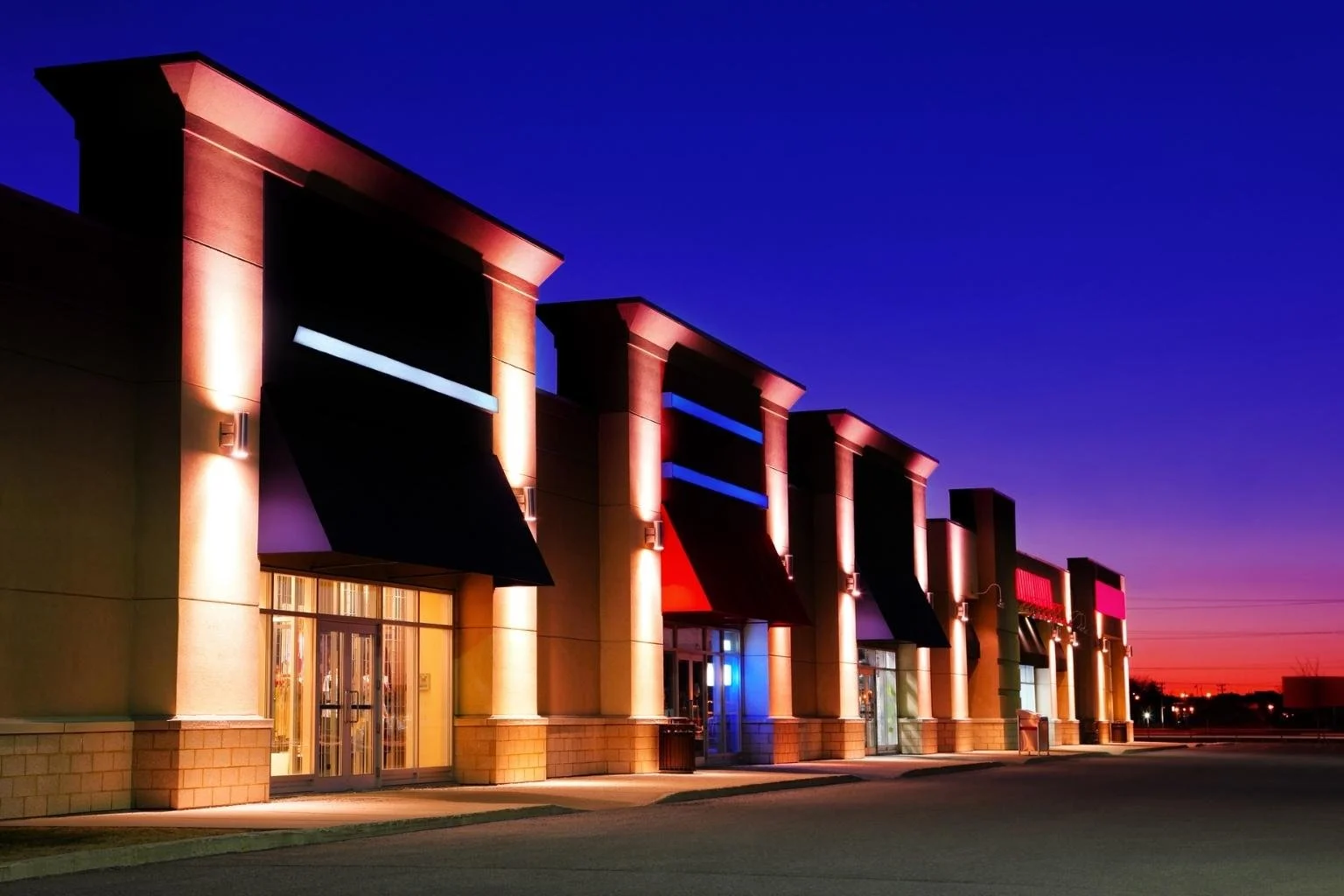Commercial electrical services installing and maintaining exterior building lighting and accent lighting for a retail storefront at night.