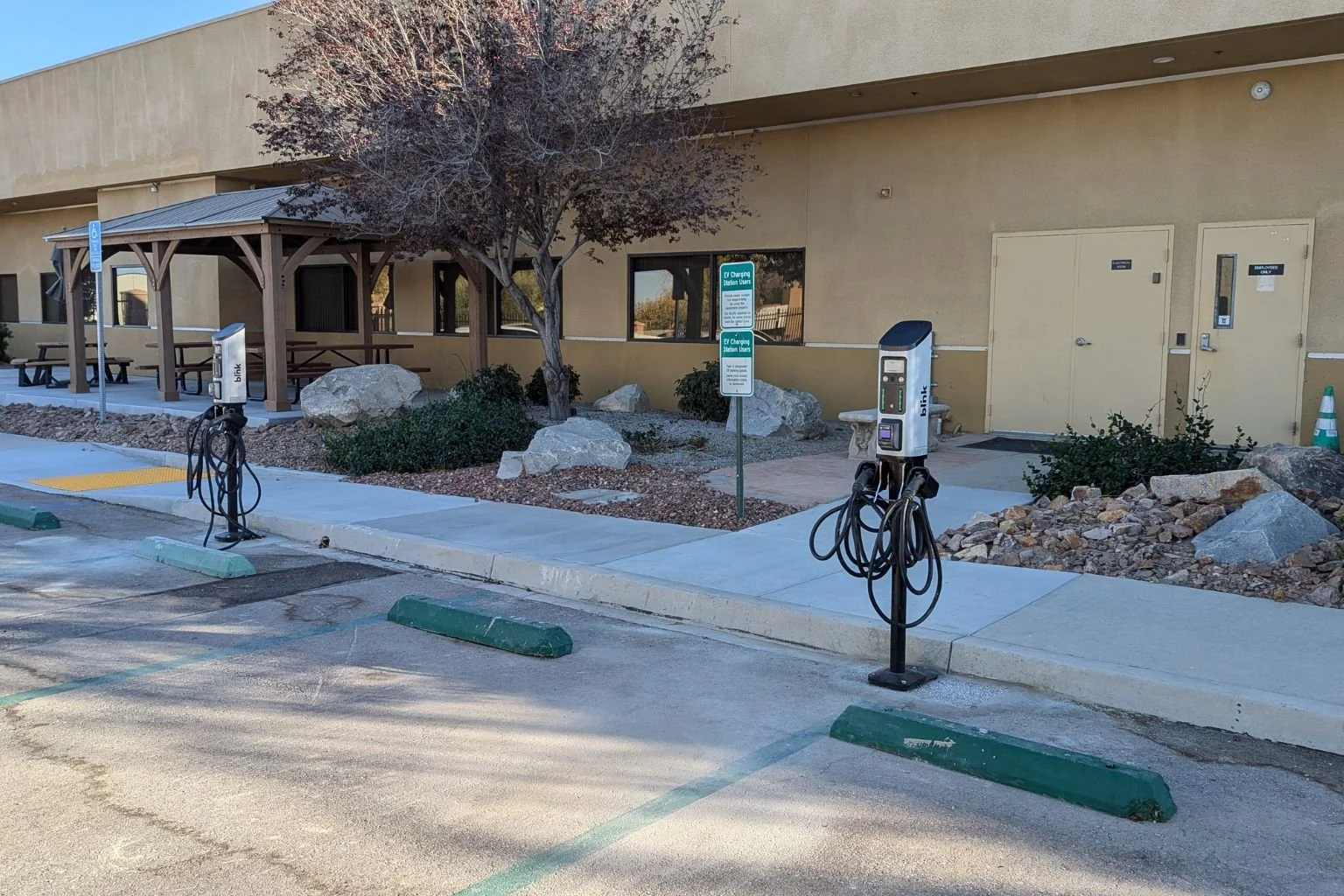 Electrician troubleshooting and repairing commercial EV charger wiring at an office building in Victorville, California after diagnosing undersized electrical conductors causing charging station failures.