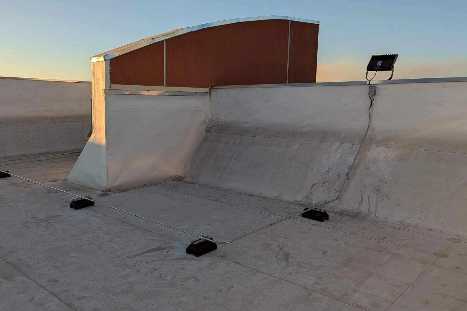 Electrical conduit installed on rooftop conduit stands by MTE Electric to supply power to LED floodlights at the Cycle Gear building in Victorville, CA, improving commercial parking lot lighting and safety.