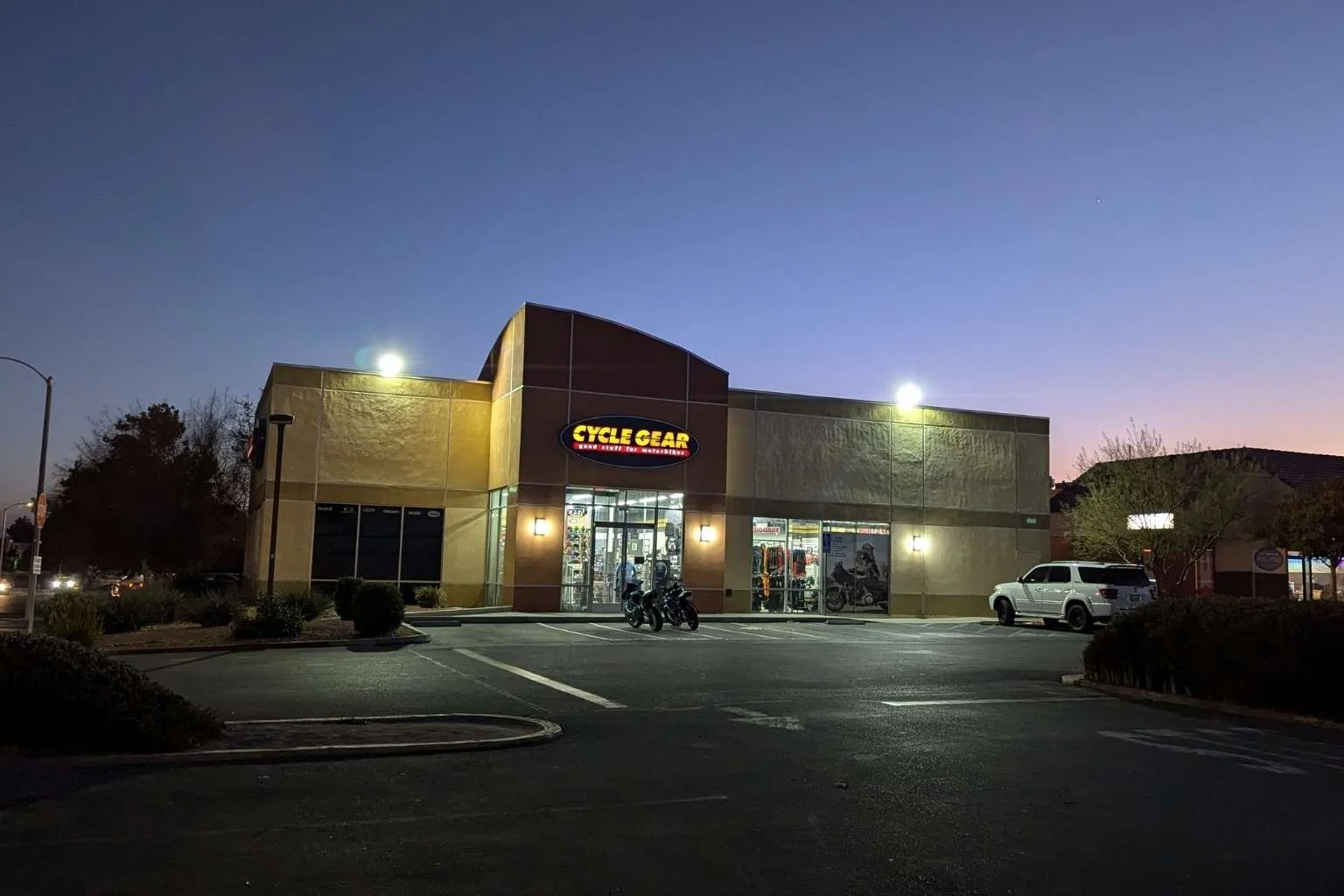 Commercial LED flood lighting installation by MTE Electric at Cycle Gear in Victorville California with illuminated parking lot at dusk.
