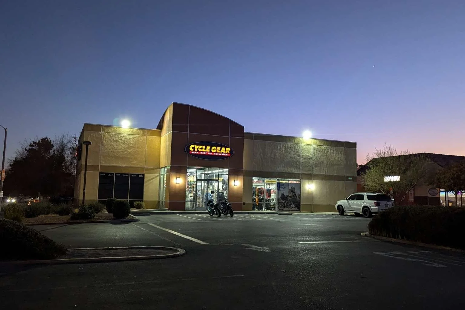Cycle Gear storefront in Victorville at dusk, illuminated by new commercial LED floodlights installed atop the building to light up the front parking lot.