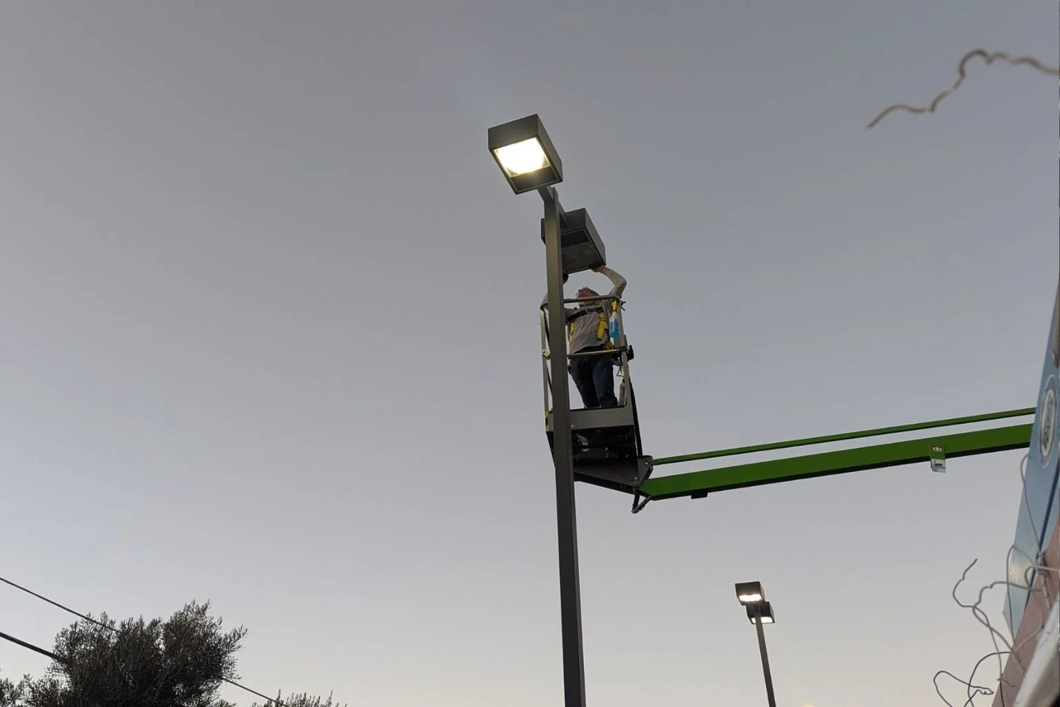 Our electrician in a boom repairing a parking lot light fixture and electrical wiring.