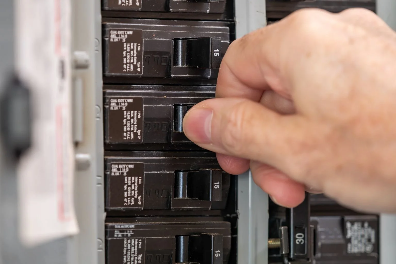Electrician safely turning off circuit breaker in electrical panel to protect employees and tenants in Apple Valley, Hesperia, and Victorville.