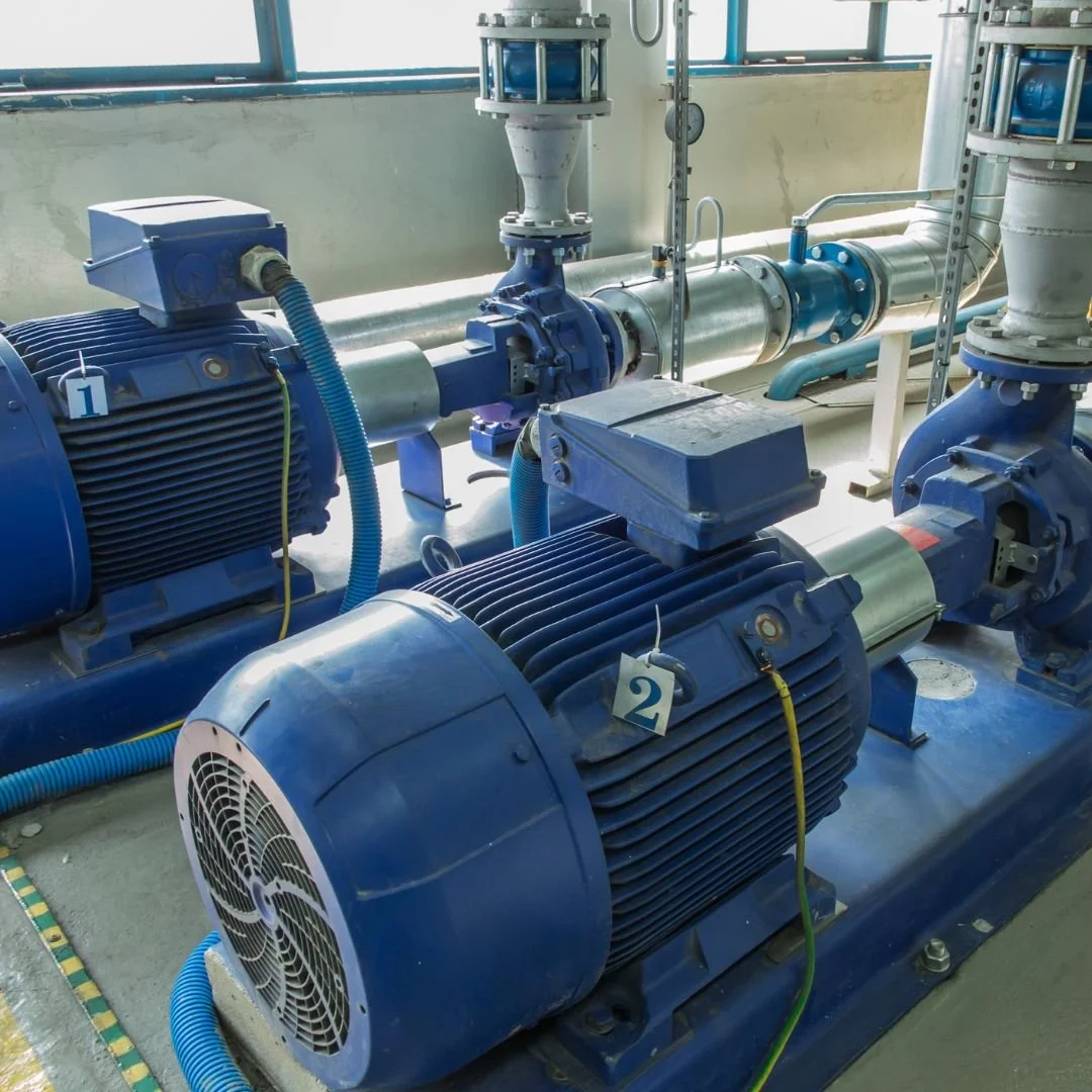 Industrial electric motors connected to a pump system with conduit and wiring, showing a professional electrical installation.