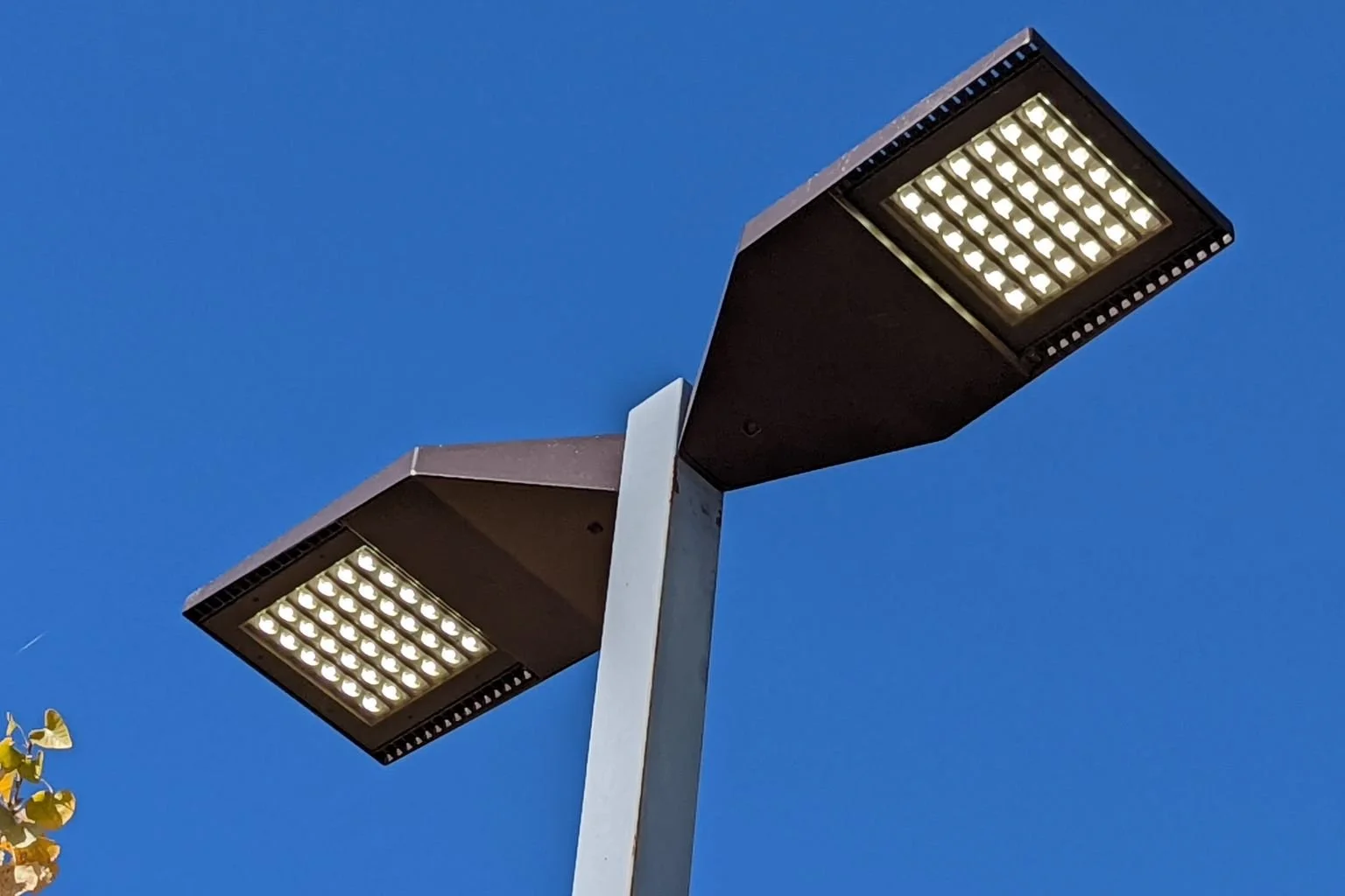 Close-up view of newly installed LSI LED parking lot light fixtures replacing outdated metal halide lights at a commercial service station in Apple Valley, CA.