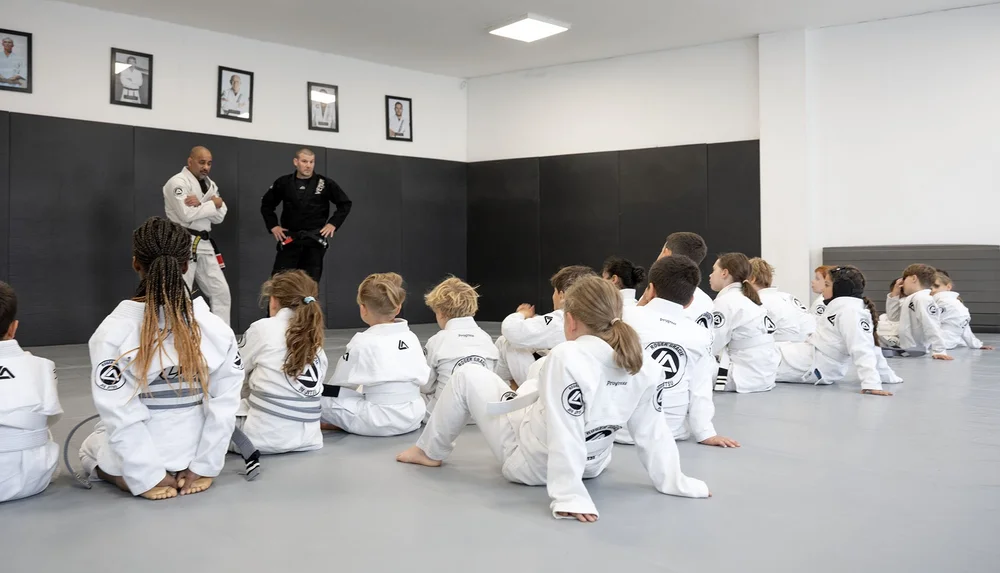Children listening to two instructors during a Jiu Jitsu class