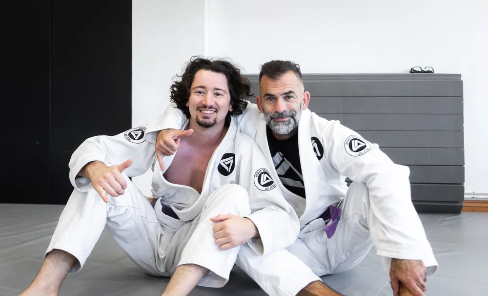 Two students smiling together on the academy mats