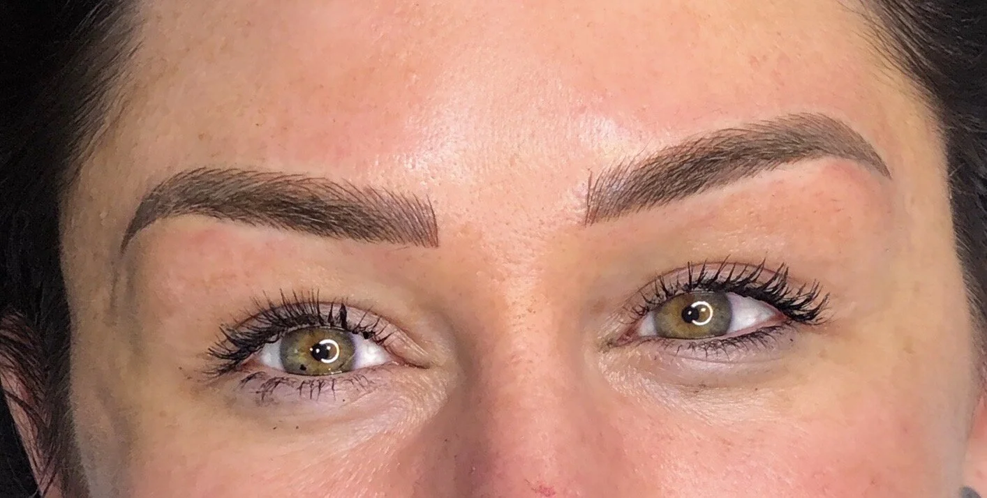 Close-up of a woman's face focusing on her eyebrows, eyes, and upper nose, showing well-groomed eyebrows and brown eyes.