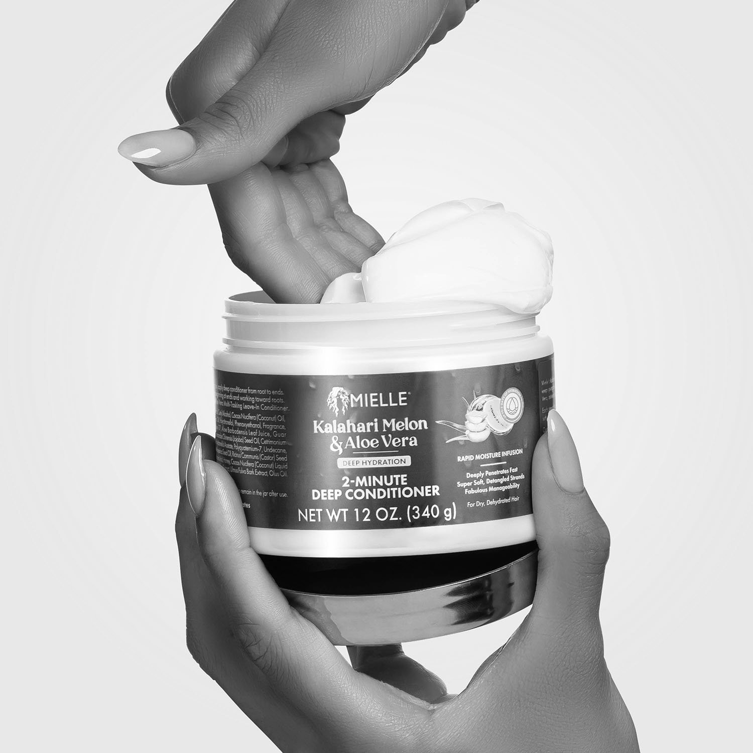 Close up of feminine hands scooping rich cream conditioner from open product container.