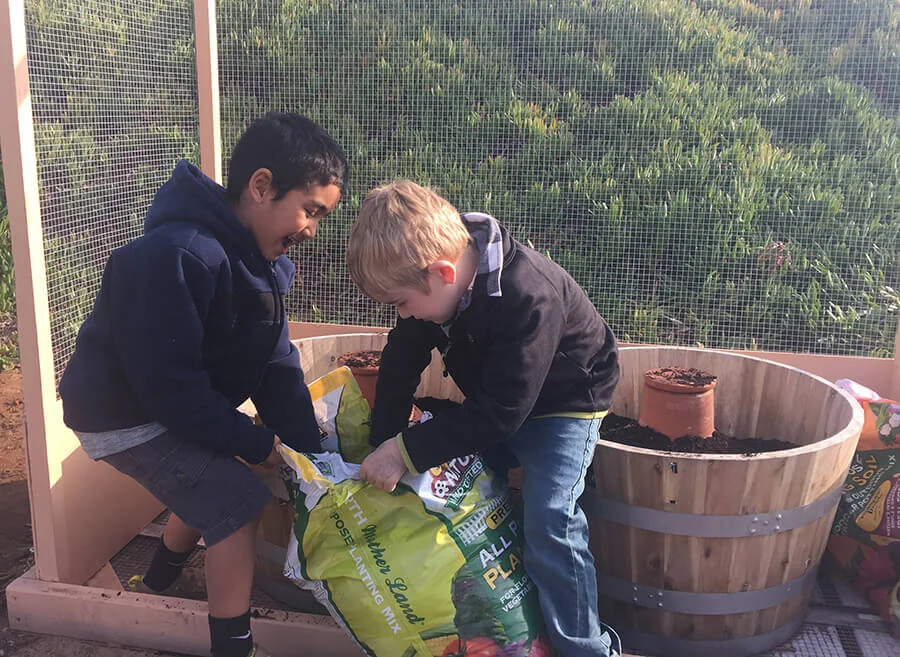 ��������-kindergarten-students-adding-potting-soil-to-school-garden-planters.jpg