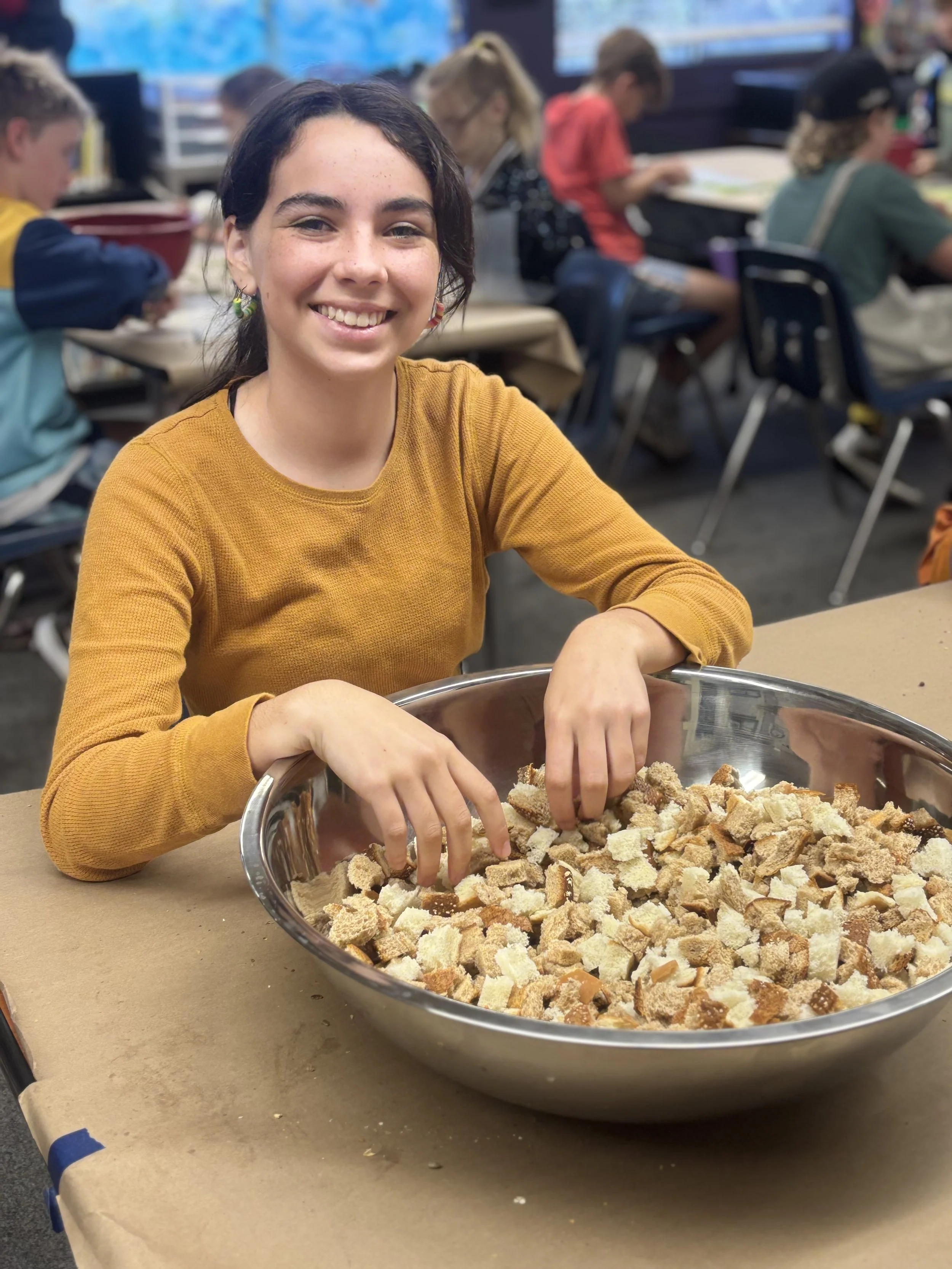 Student preparing Thanksgiving stuffing and smiling