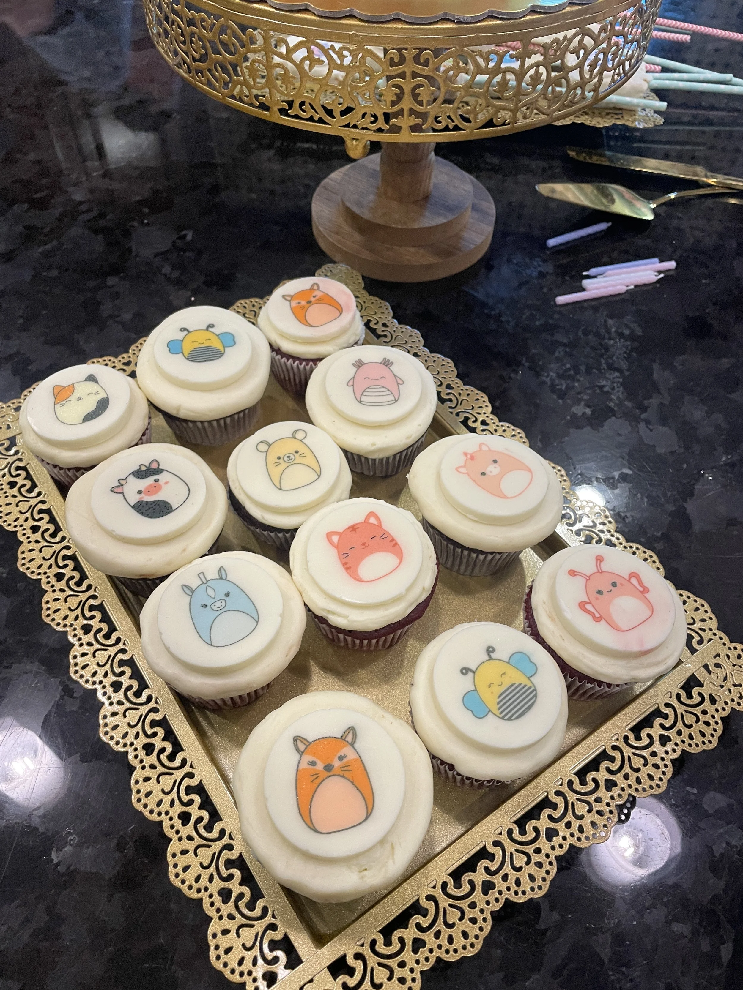 White cupcakes with hand-painted floral designs on a gold tray
