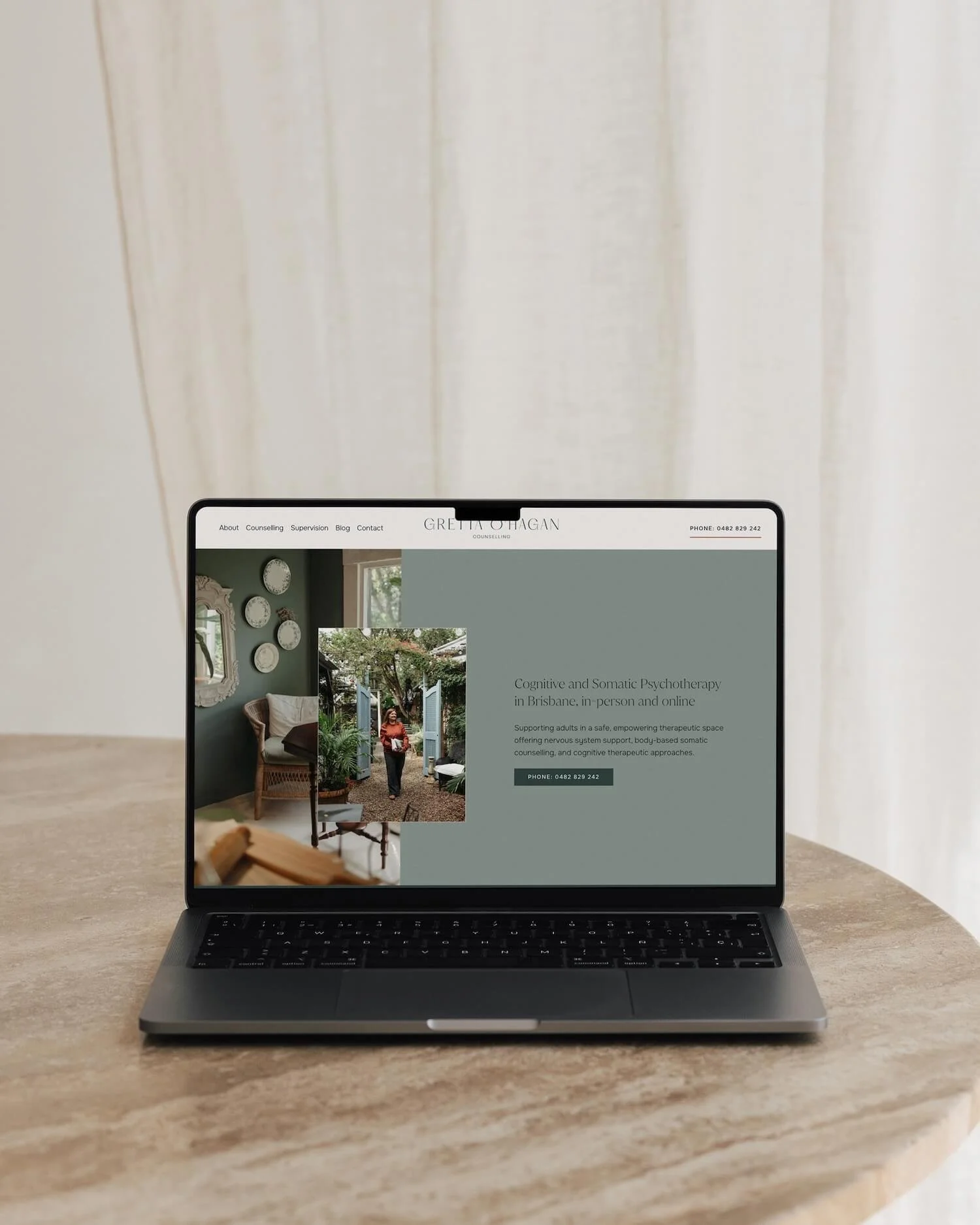 Laptop displaying a soft green and neutral-toned therapy website, showcasing website design for somatic therapist with calming imagery and clear navigation.