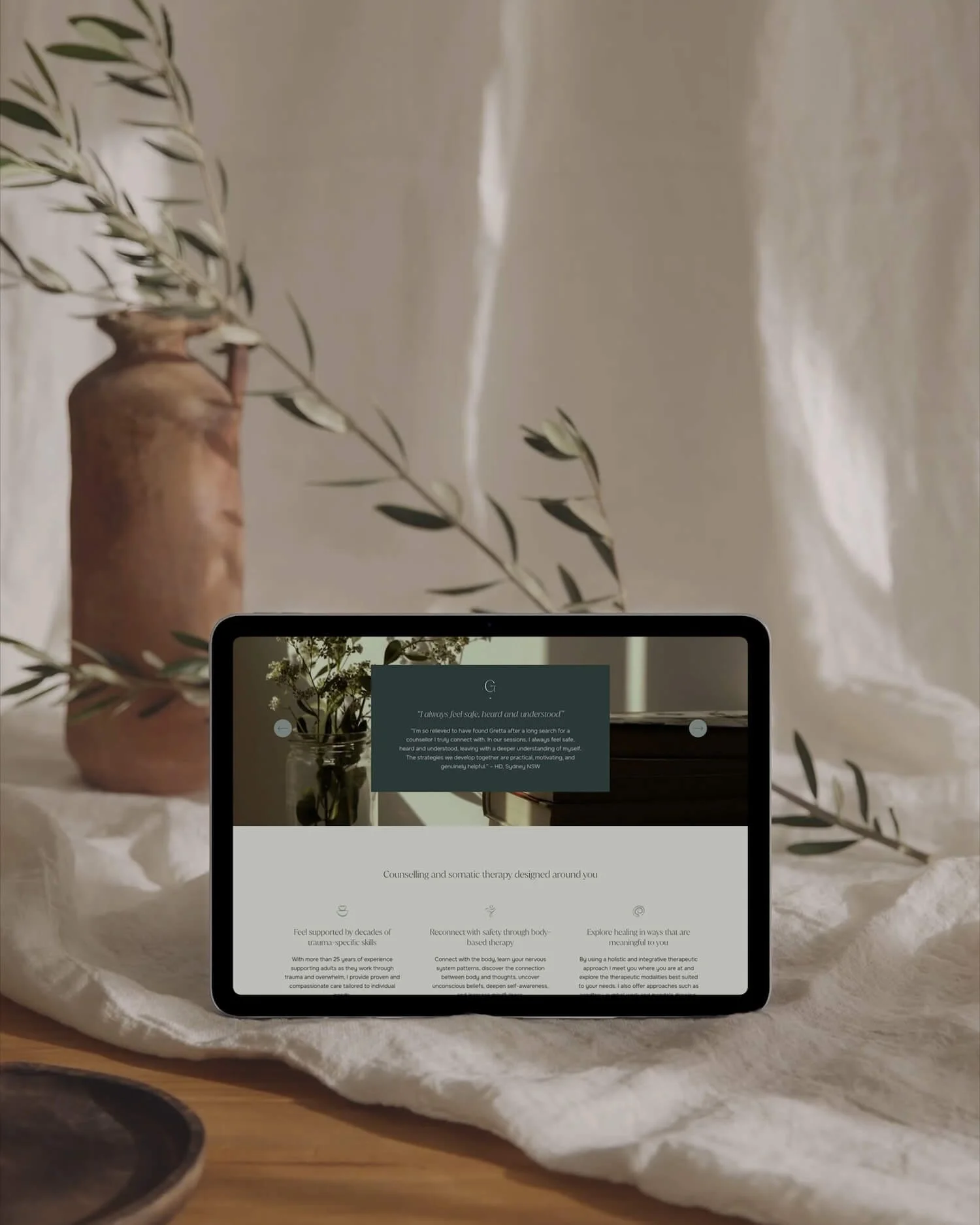 Tablet displaying testimonial section of a counselling website, styled with natural textures and greenery.