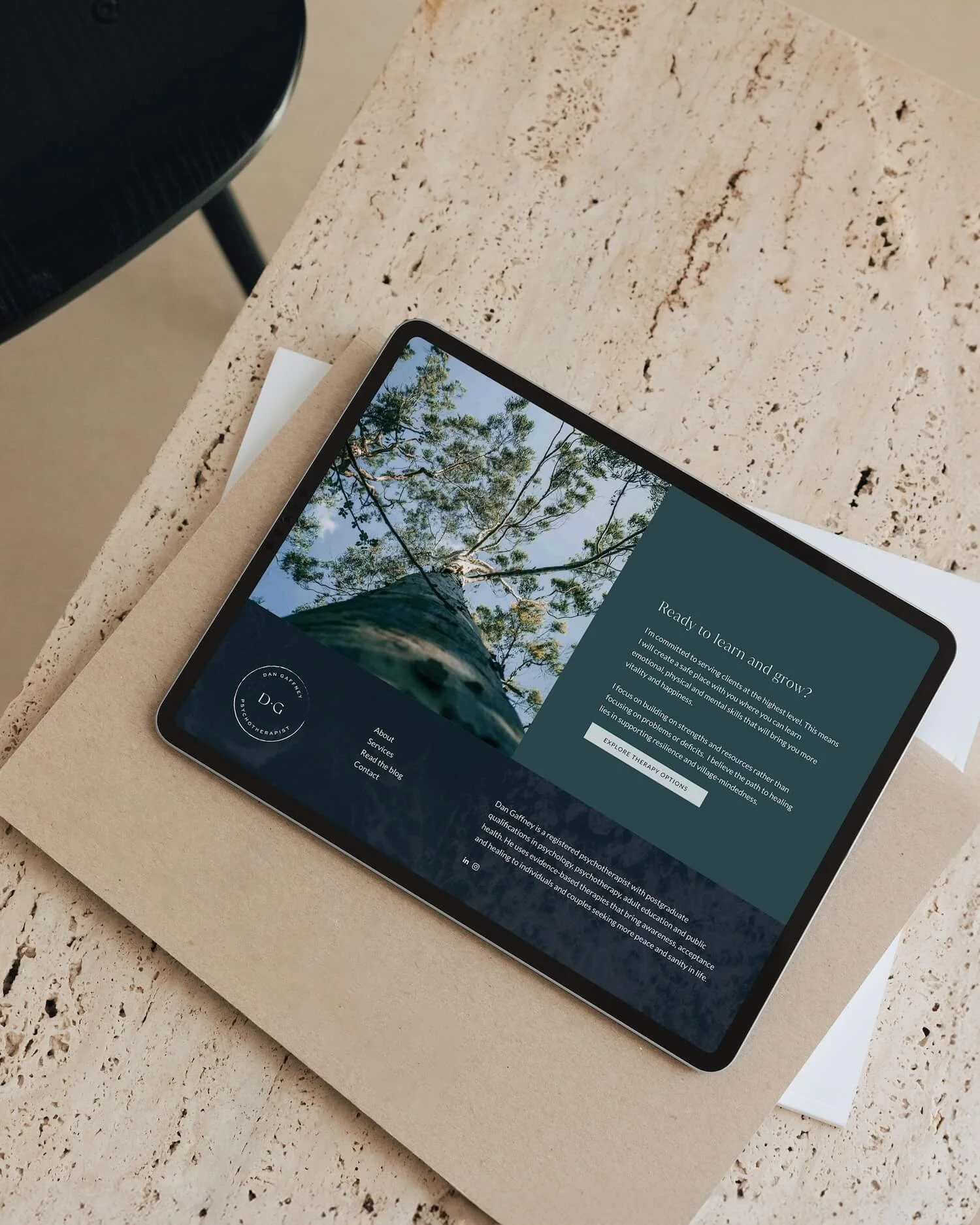 Squarespace iPad mockup showing the footer of the Dan Gaffney Psychotherapist website, with a nature photography background overlaid in deep bottle green and the circular DG brand mark.
