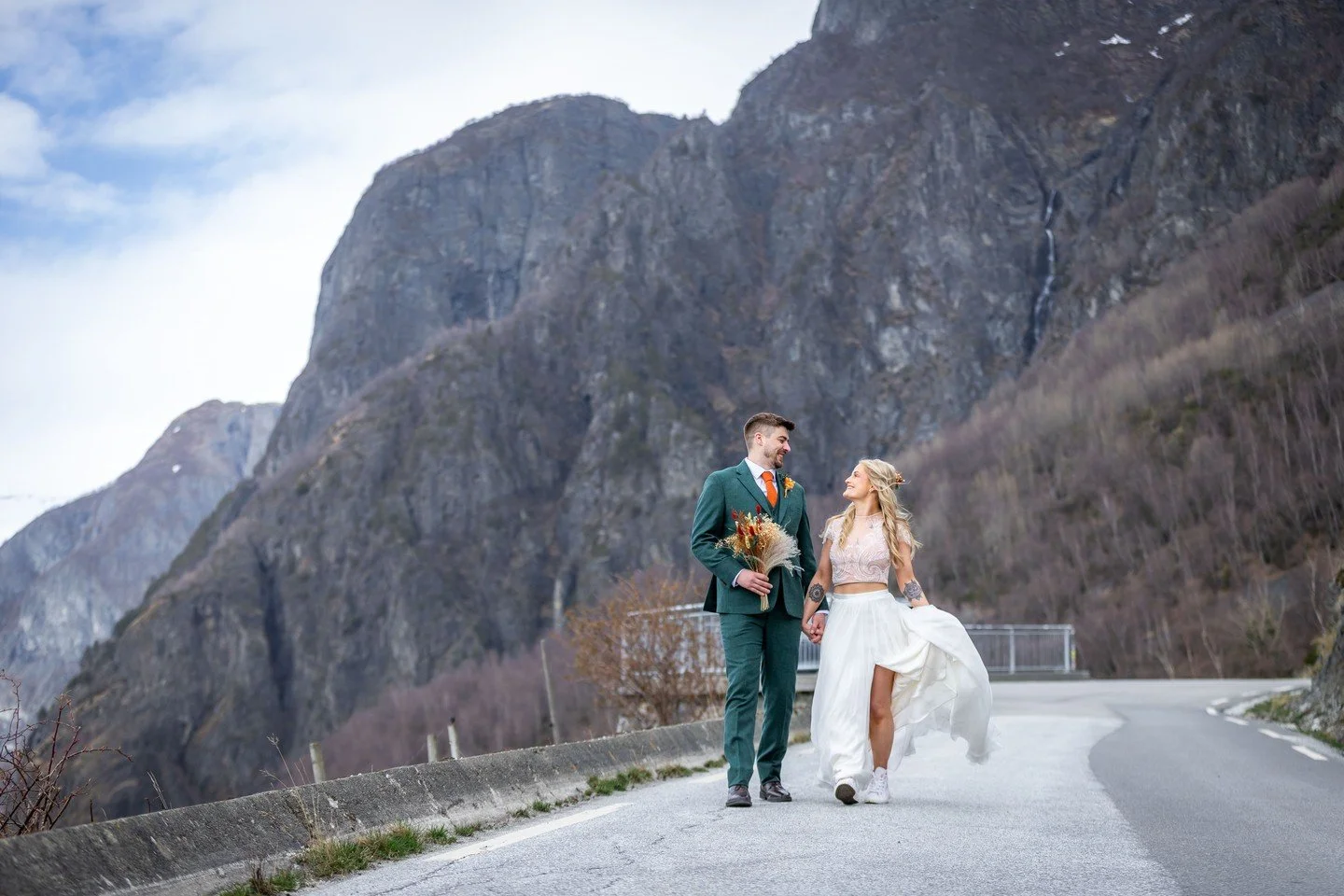 Dark green suit. Orange tie. White two-piece. White sneakers. A bouquet that does not apologise for itself.

And behind them, Norway.

There is no dress code for a Fjord Wedding. There are no rules about what you are supposed to wear, how you are sup