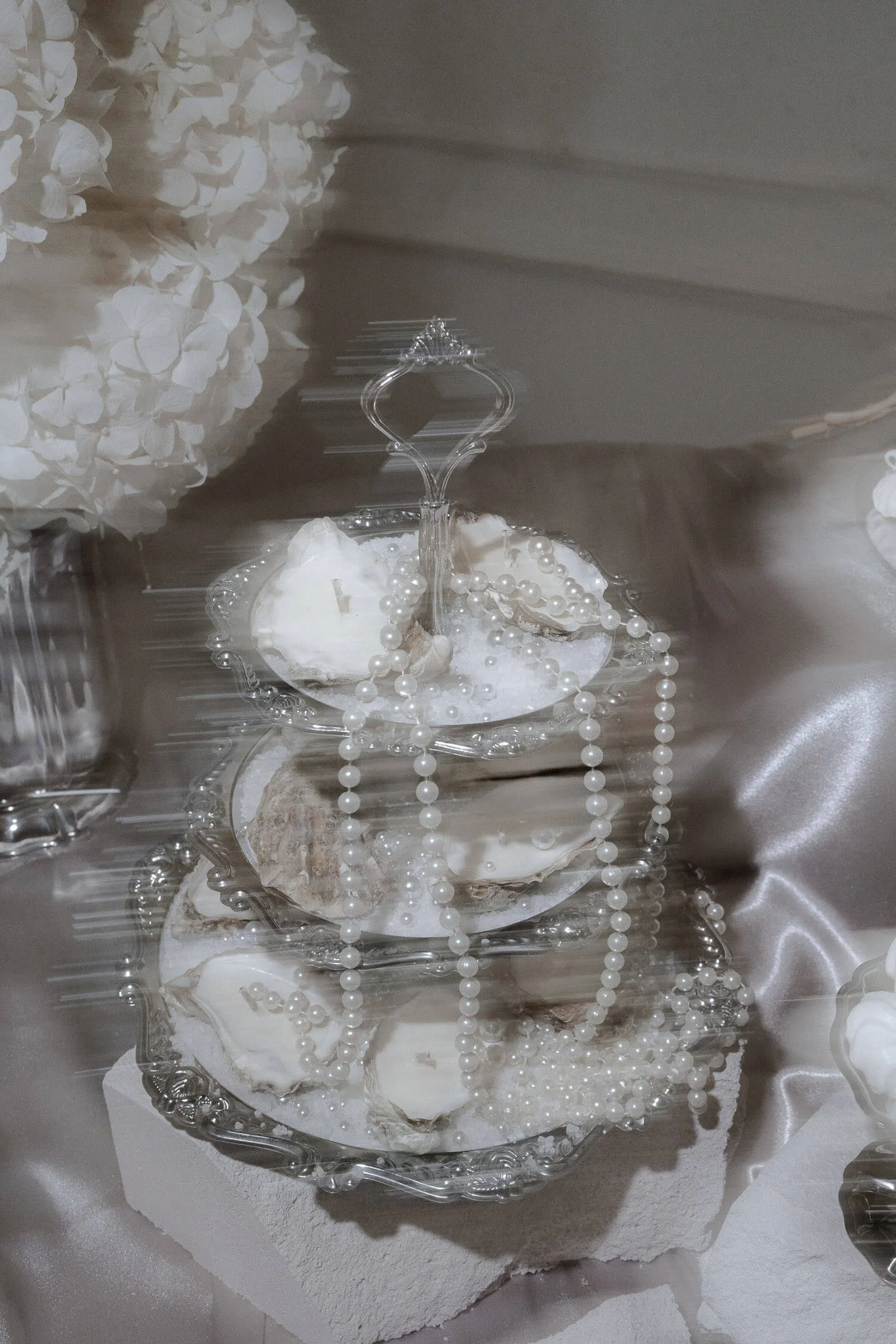 Edles Hochzeitsdetail mit Perlen, Austernschalen und silbernem Etageren-Setup