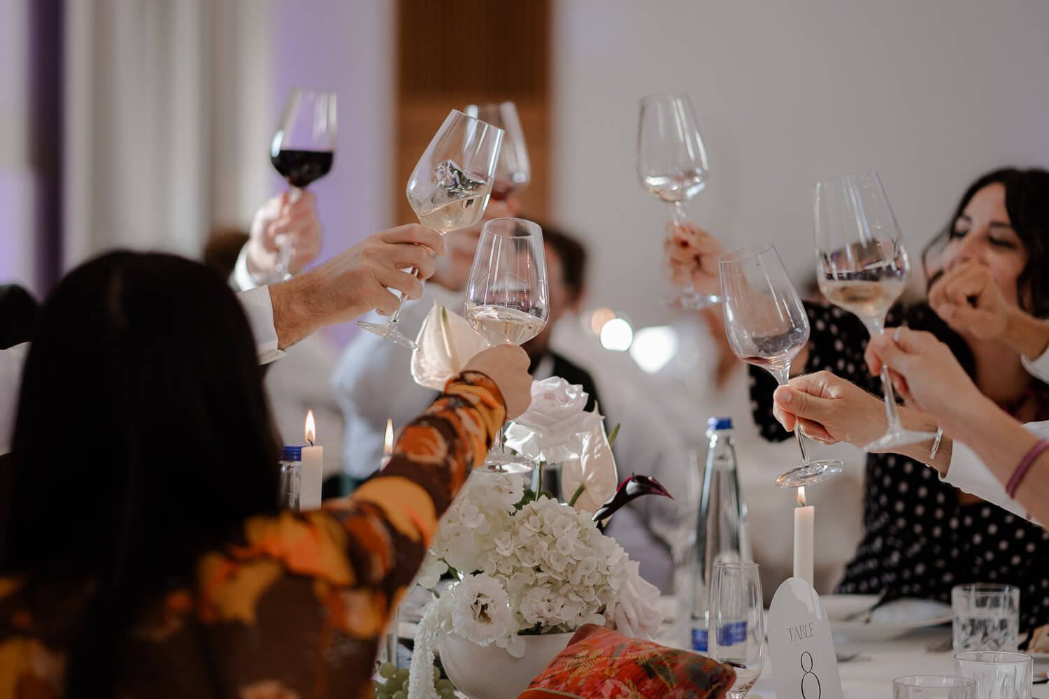 Gäste feiern mit Weingläsern im Hochzeitssaal.