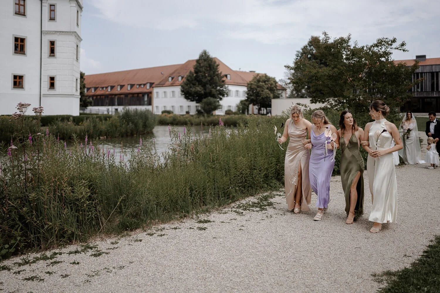 Brautjungfern gehen lachend an Teich entlang