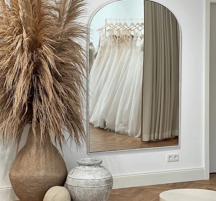 Brautkleid München: Spiegel zeigt Reihe eleganter Kleider neben Pampasgras-Deko
