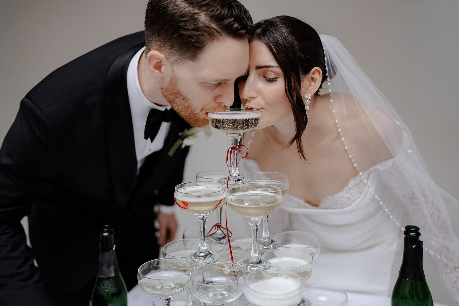 Brautpaar trinkt Sekt aus Glasturm bei Hochzeit.