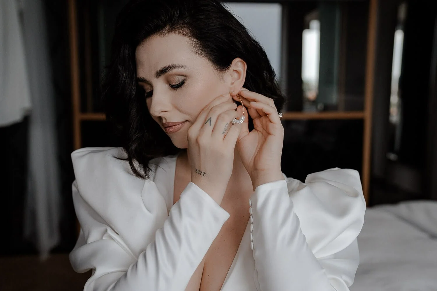 Braut steckt Ohrring an, getting ready im andaz munich