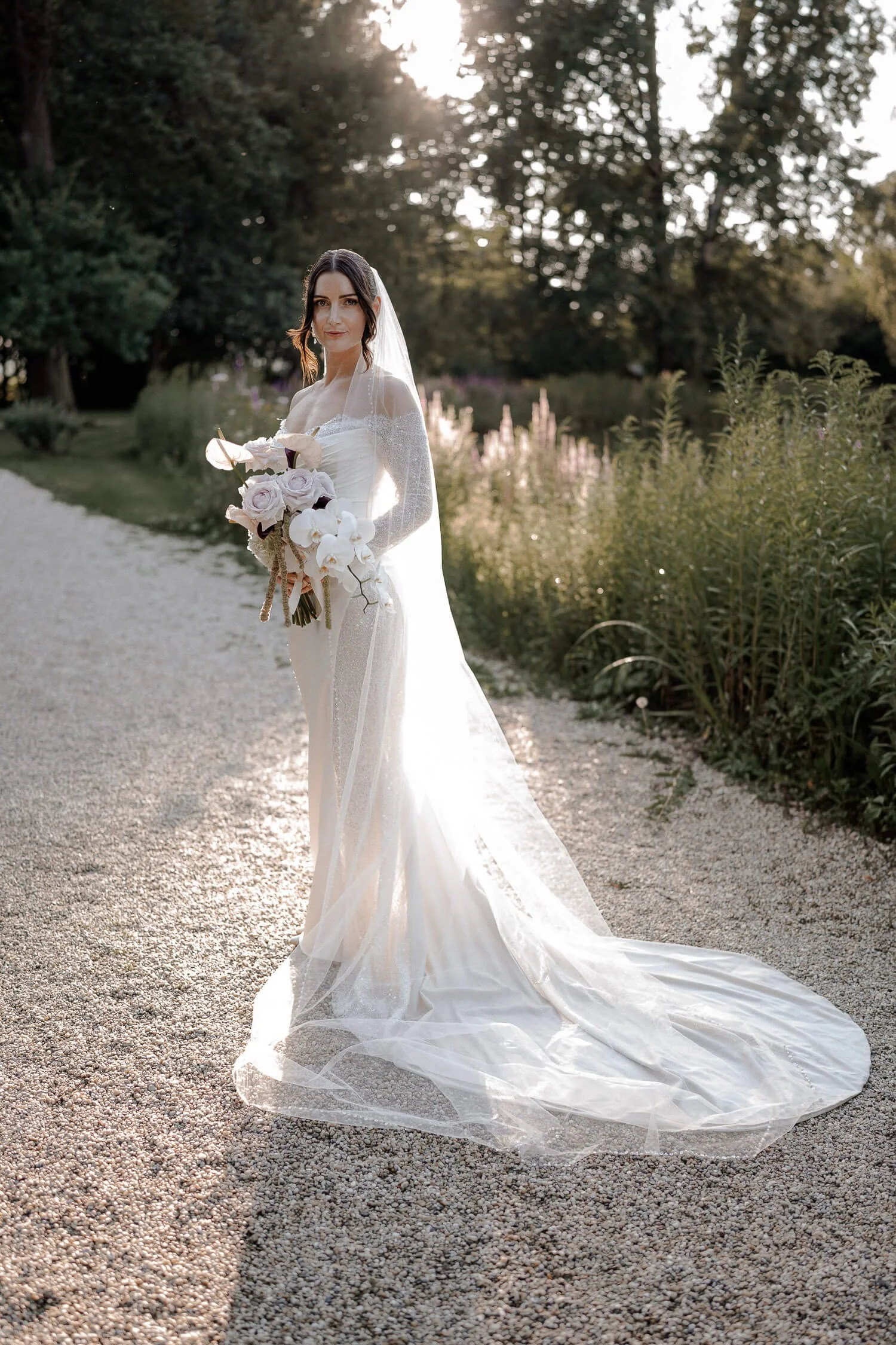 Braut mit Schleier und Brautstrauß im Park von Schloss Hohenkammer.