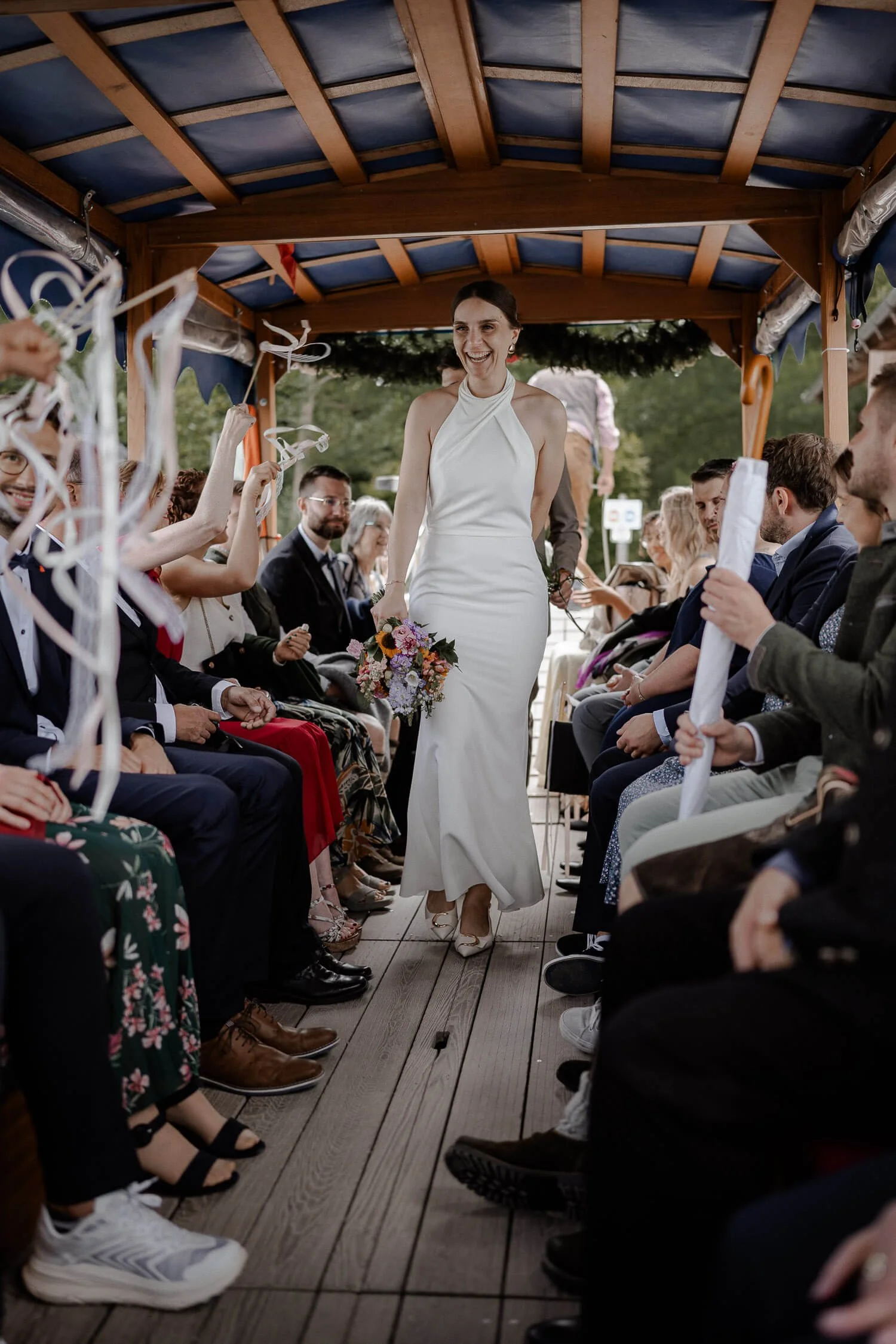Braut geht durch Spalier im Boot (Ribbon-Wands), Gäste links/rechts, jubelnd – hochzeit boot roseninsel einzug spalier bänder reportage