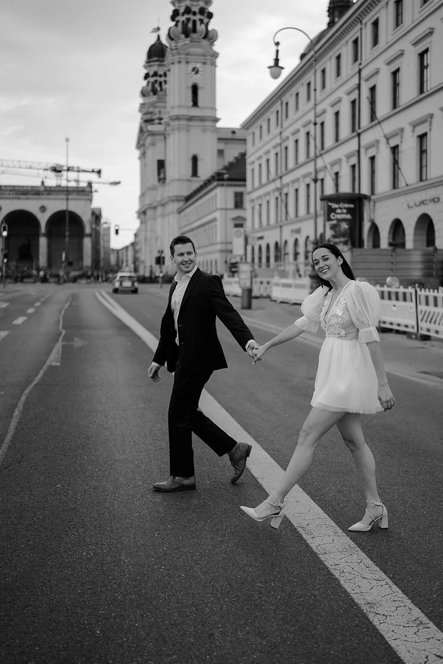 Engaged couple walking across Odeonsplatz street