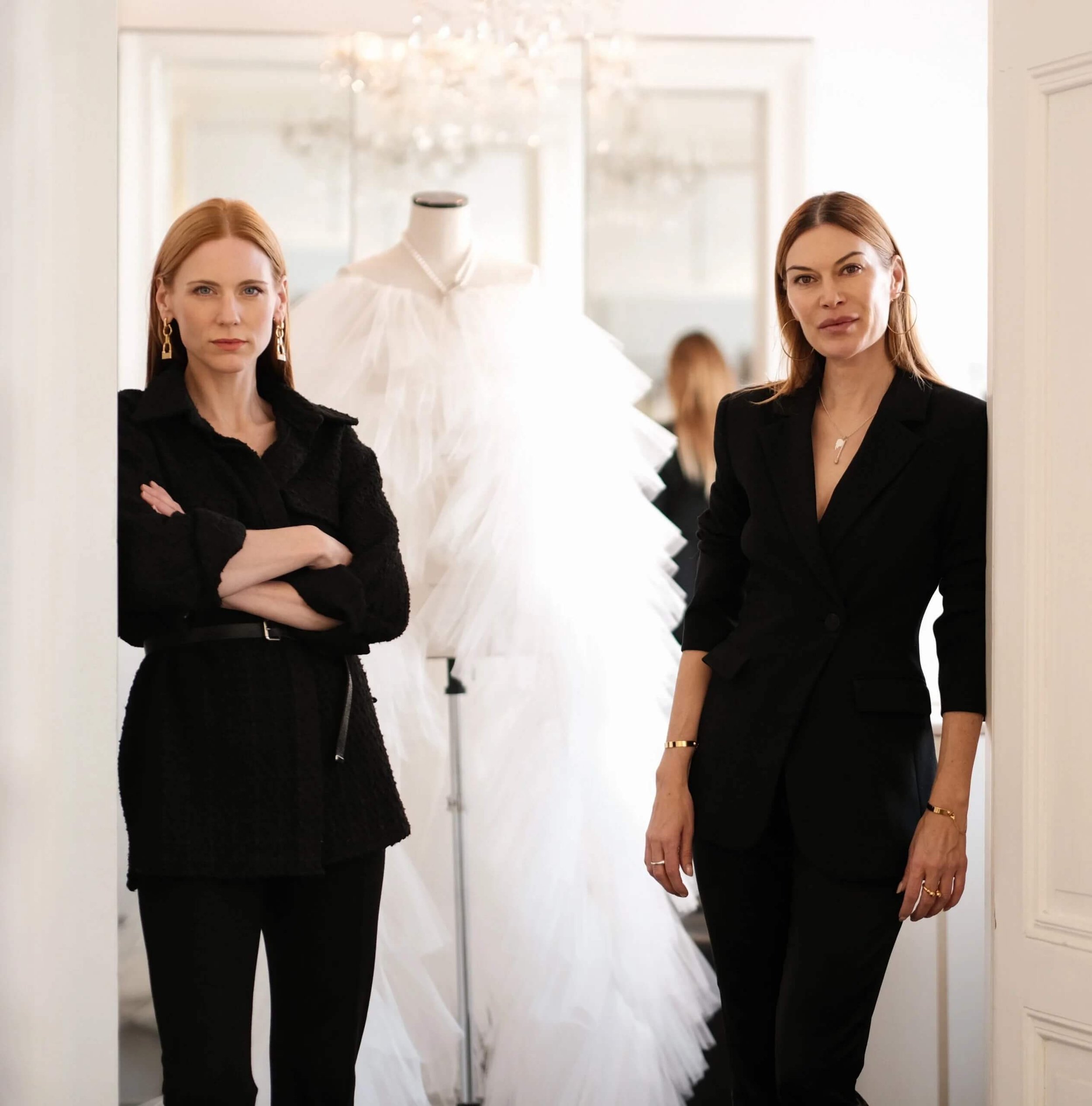 Brautmode München: zwei Designerinnen im Atelier vor Tüll-Brautkleid auf Puppe