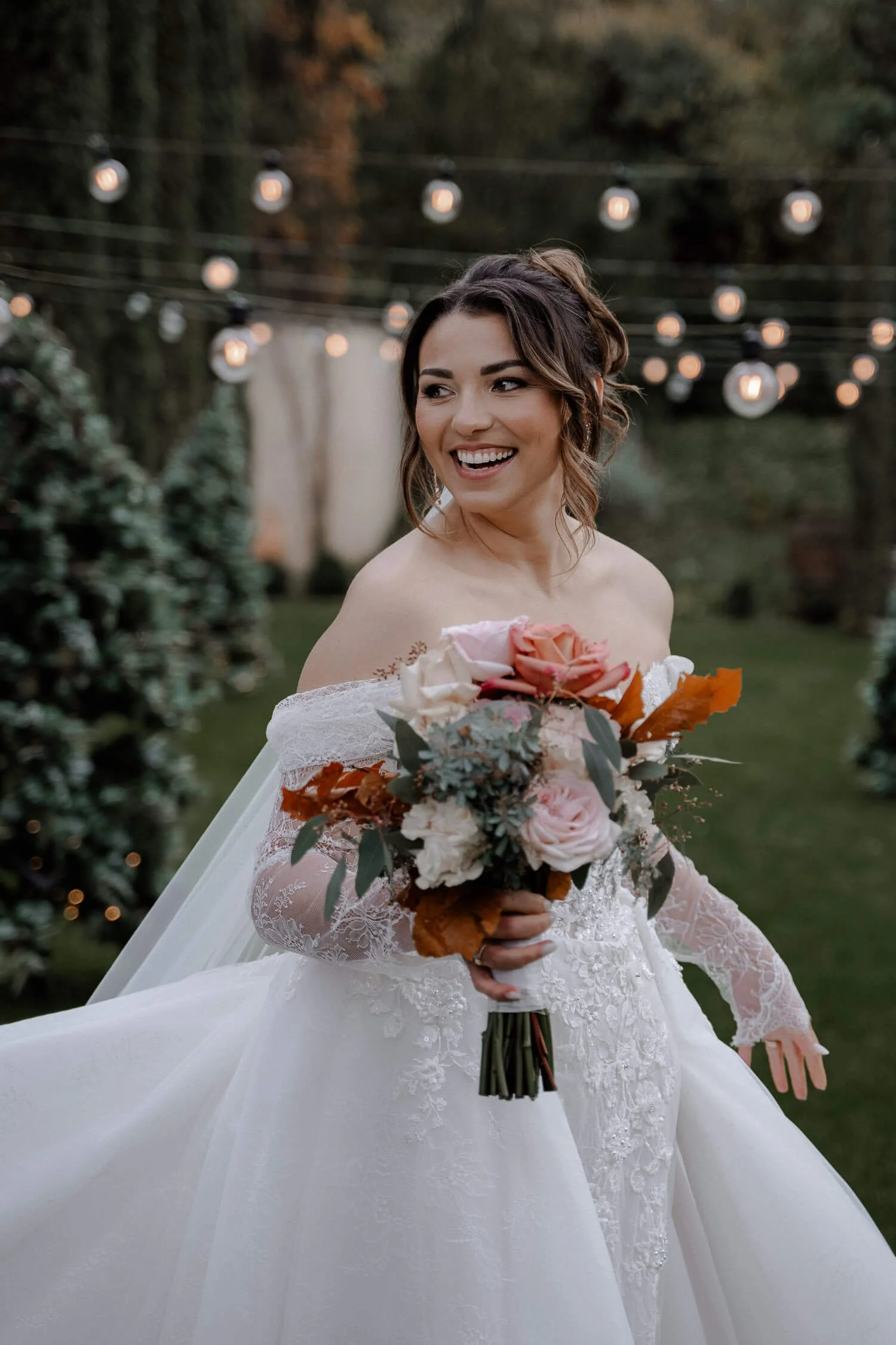 Braut mit Strauß unter Lichterketten
