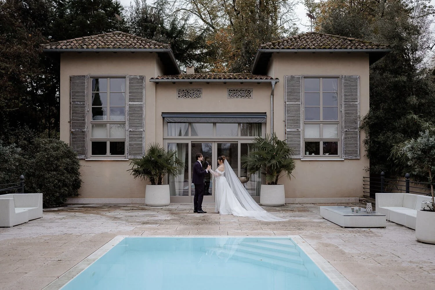 Brautpaar vor modernem Badehaus mit Pool im Morrhof
