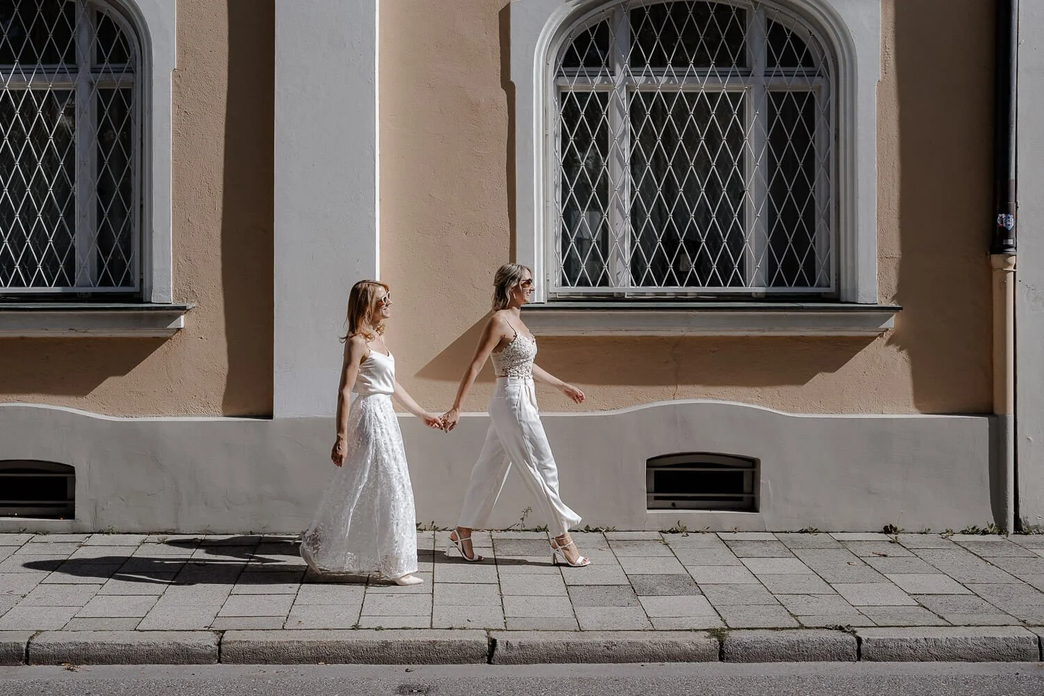Zwei Frauen laufen Hand in Hand am Standesamt Mandlstraße München vorbei