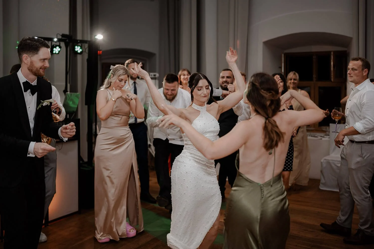 Braut tanzt ausgelassen mit Gästen bei Hochzeit.