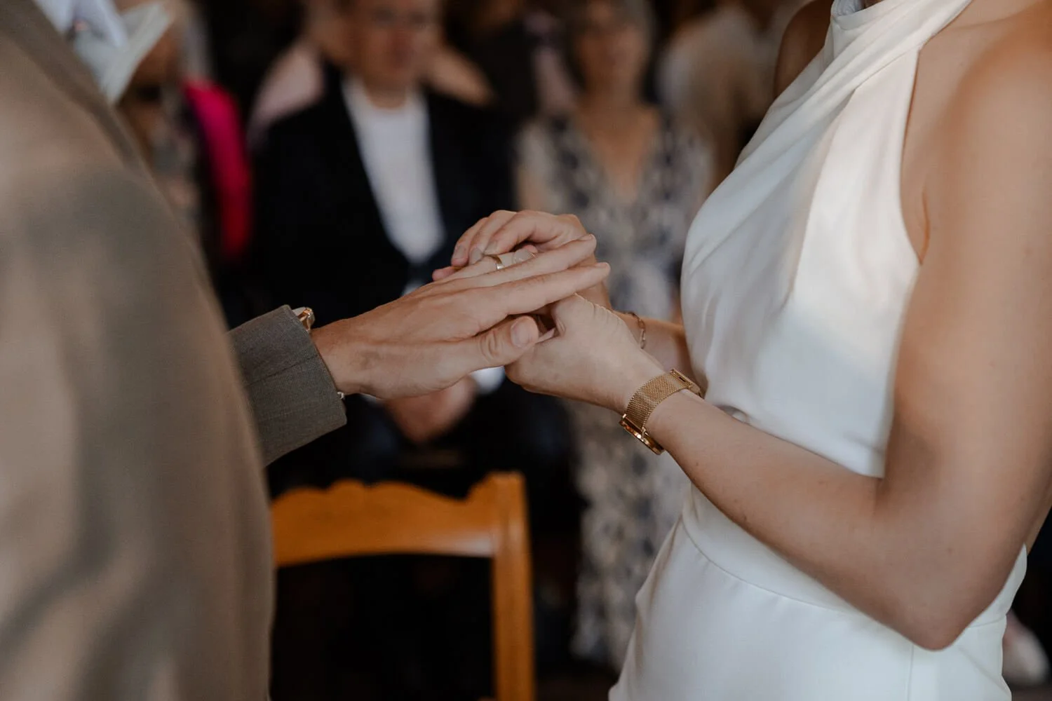 Bräutigam steckt Ring an, Gäste im Hintergrund – heiraten auf der roseninsel