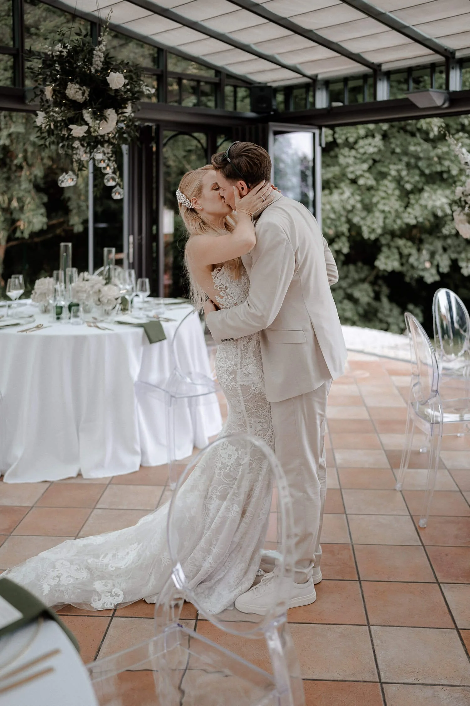 Kuss des Brautpaars im lichtdurchfluteten Wintergarten vom La Villa in Starnberg