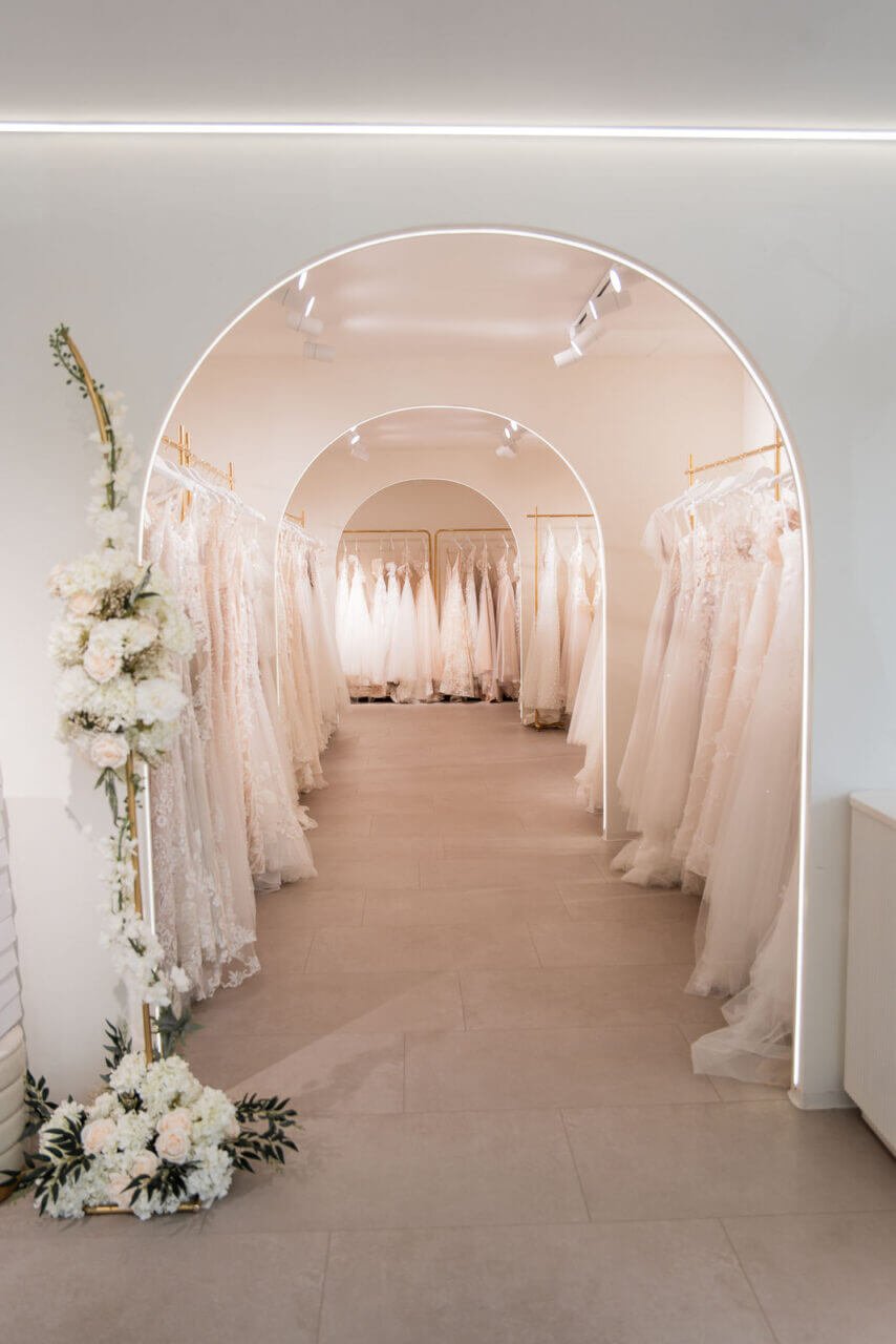 Brautmode München: Showroom mit Bögen, Blumen und Reihen von Brautkleidern